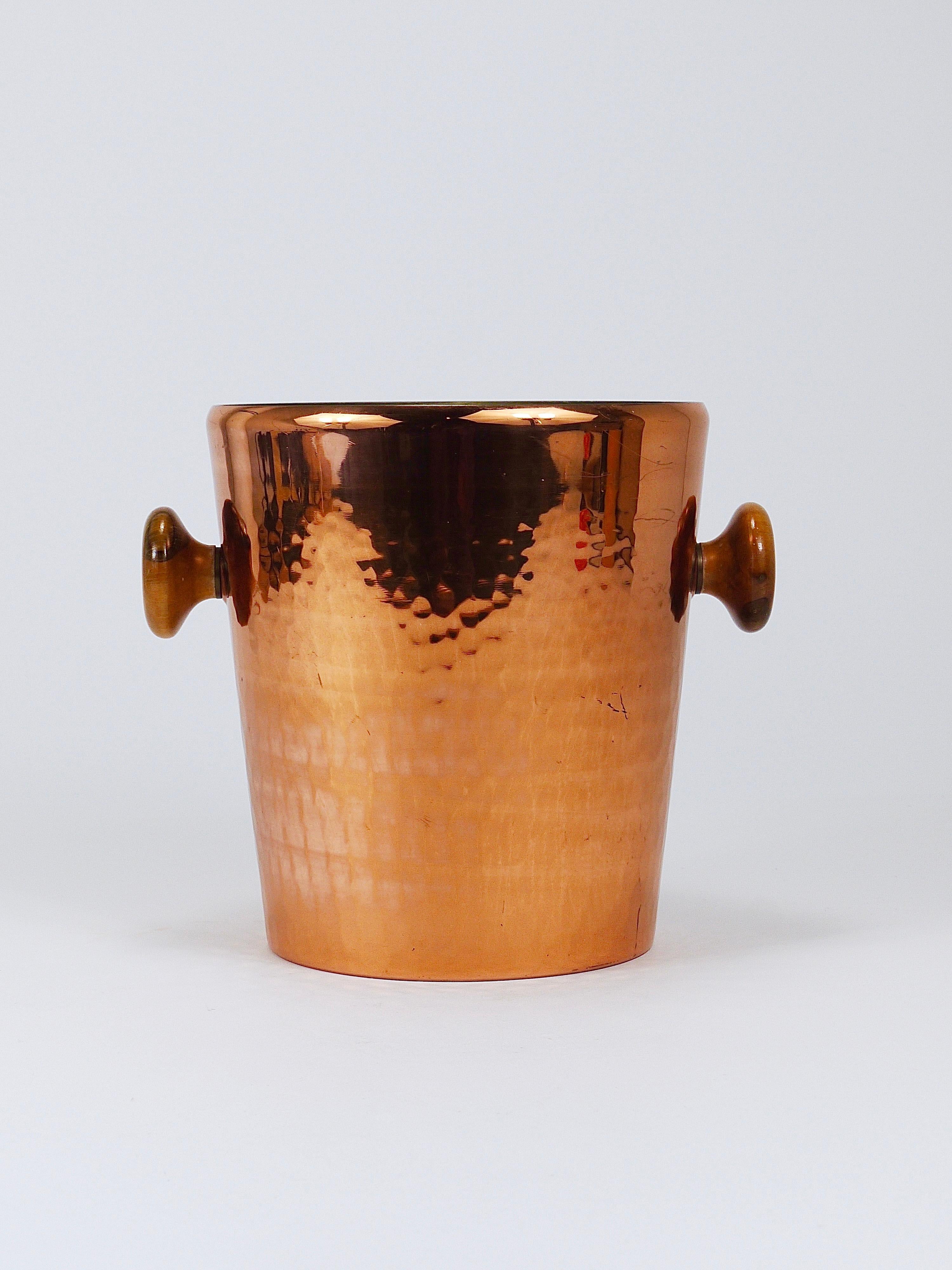 A stunning, high-end hand-forged Mid-Century champagne bucket or wine cooler from the 1950s, expertly crafted by Stöckli Netstal, Switzerland. Made from hand-hammered copper, it features elegant walnut handles accented with brass details. This