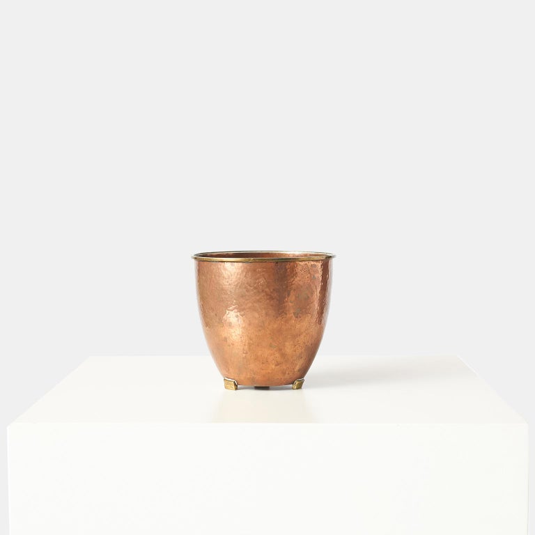 A patinated hammered copper pot with brass rim and 3 feet, by Karl Hagenauer for Werkstatten Hagenauer. Impressed on base with manufacturers mark.