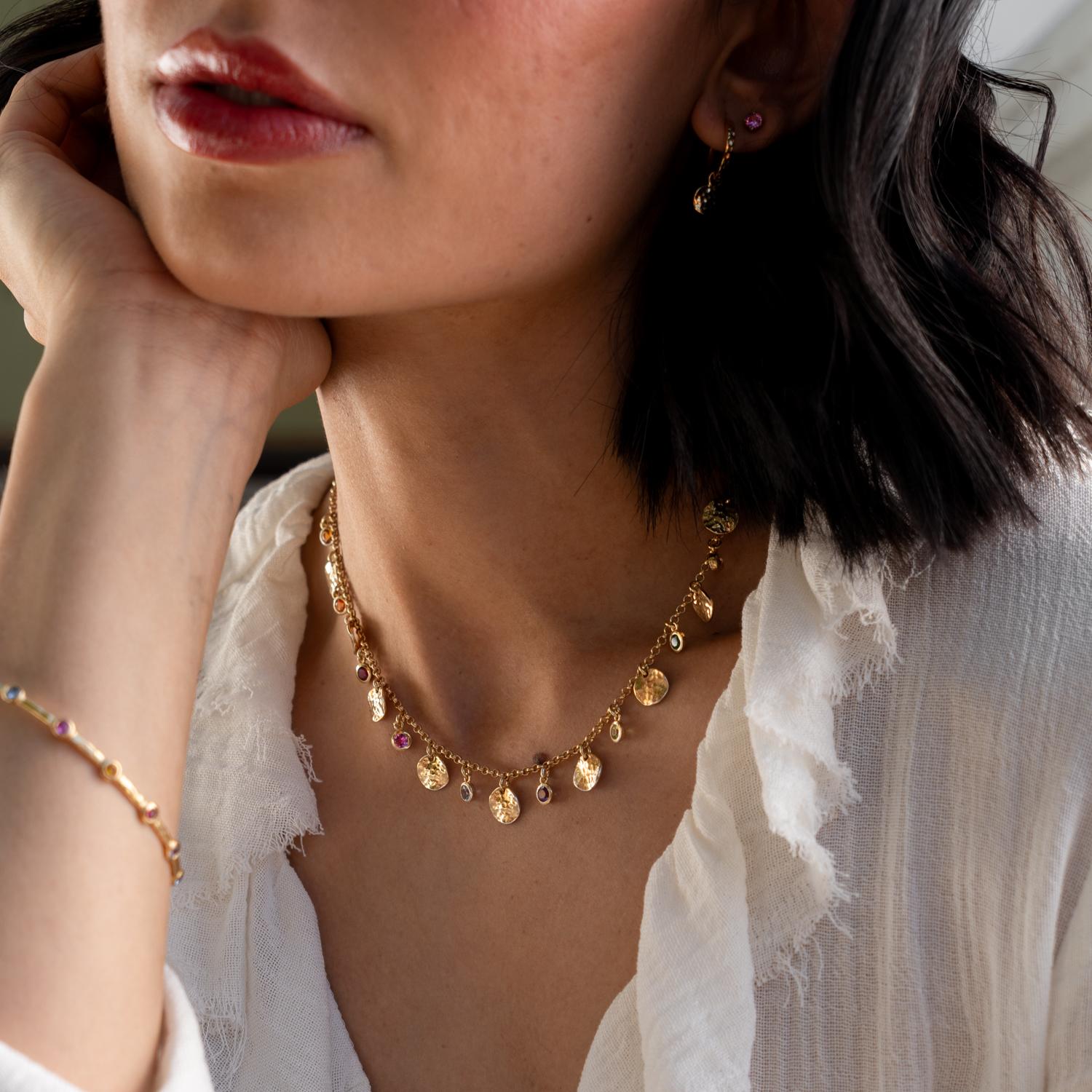 Eine moderne Interpretation traditioneller Opulenz: Diese Halskette aus Sterlingsilber vereint moderne gehämmerte Scheiben mit einem Regenbogen aus bunten Edelsteinen, die im Licht funkeln. Das Collier zeigt eine Reihe von strahlenden Edelsteinen,