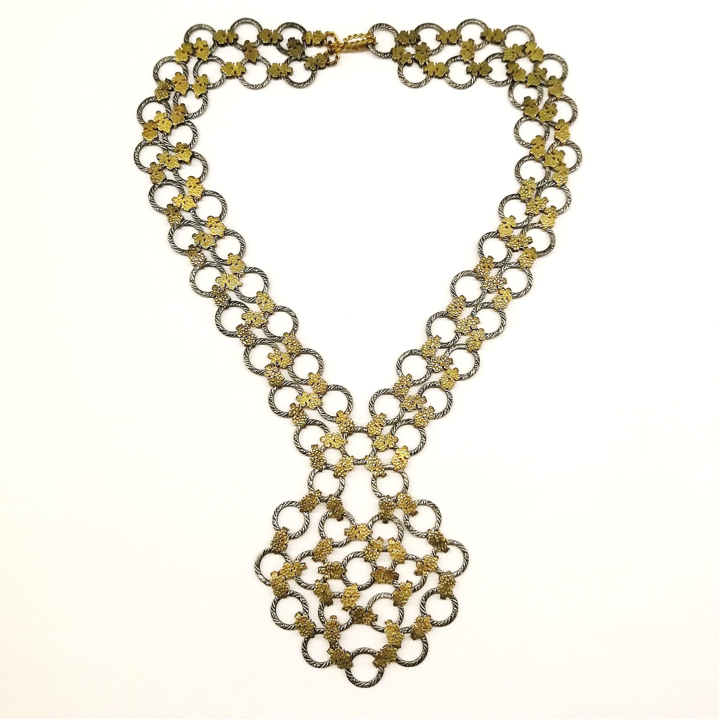 An intricate and unusually constructed necklace of circles, joined by small floral links, in both silvered and gilt metal, adding to its diversity - designed in a typical French 'sautoir' style - made by the celebrated Parisian artisan designer