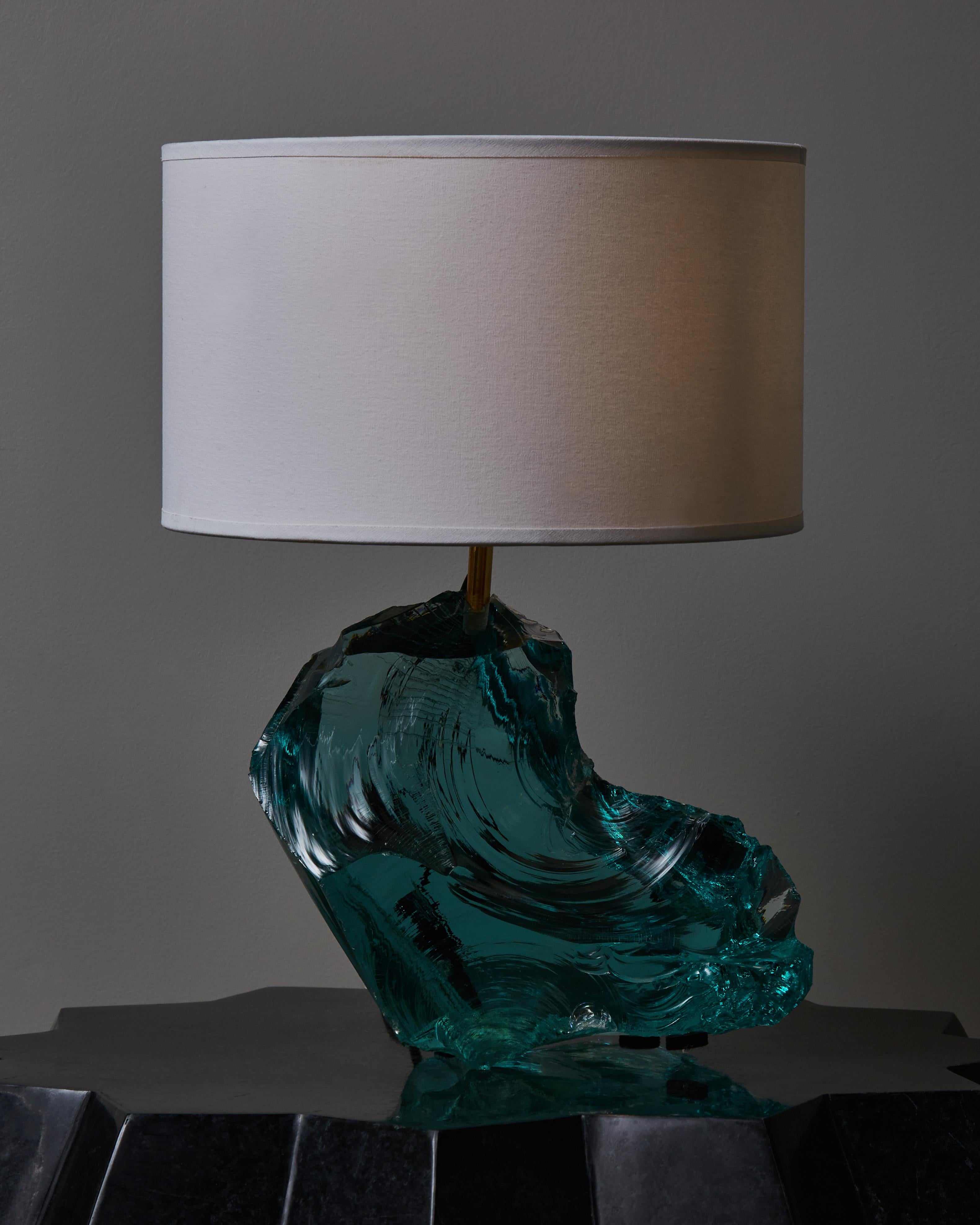 Free shaped hammered glass table lamp made of a single blue/green massive glass piece and brass fitting.