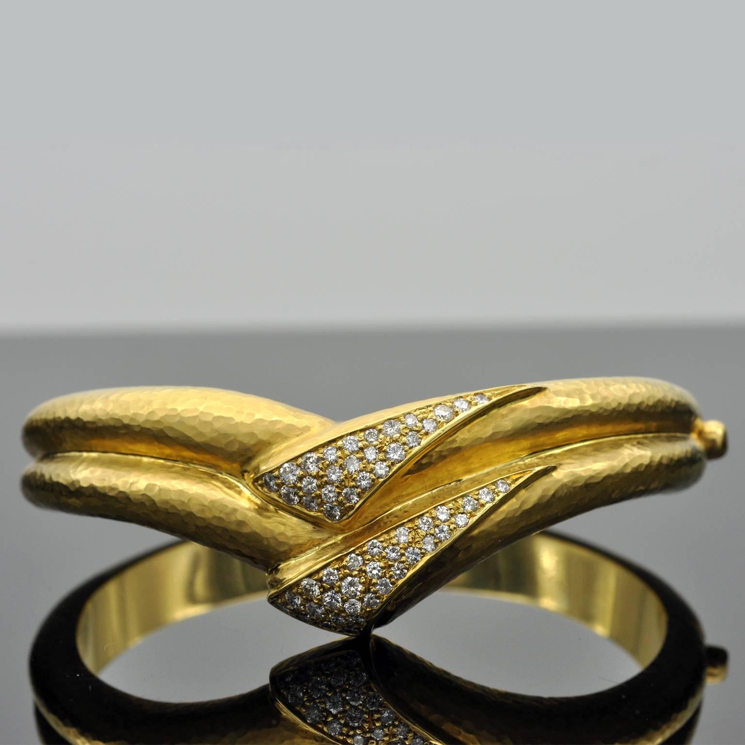 Exclusive cuff bracelet. A double band of 18 kt hand hammered yellow gold form a v-shaped central motif set with round brilliant cut diamonds. It is extremely well made: you can barely see the hinge; It smooth an pleasant in hand and sits perfectly