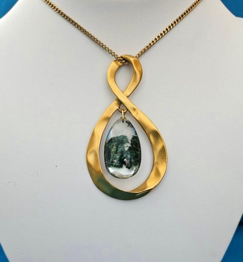 Collana con ciondolo Infinity in metallo martellato e Lodolite, in stile Mid-Century Modern
Si tratta di un bellissimo ciondolo in metallo (tono) dorato martellato, una collana di grande effetto, con all'interno una graziosa goccia di lodolite