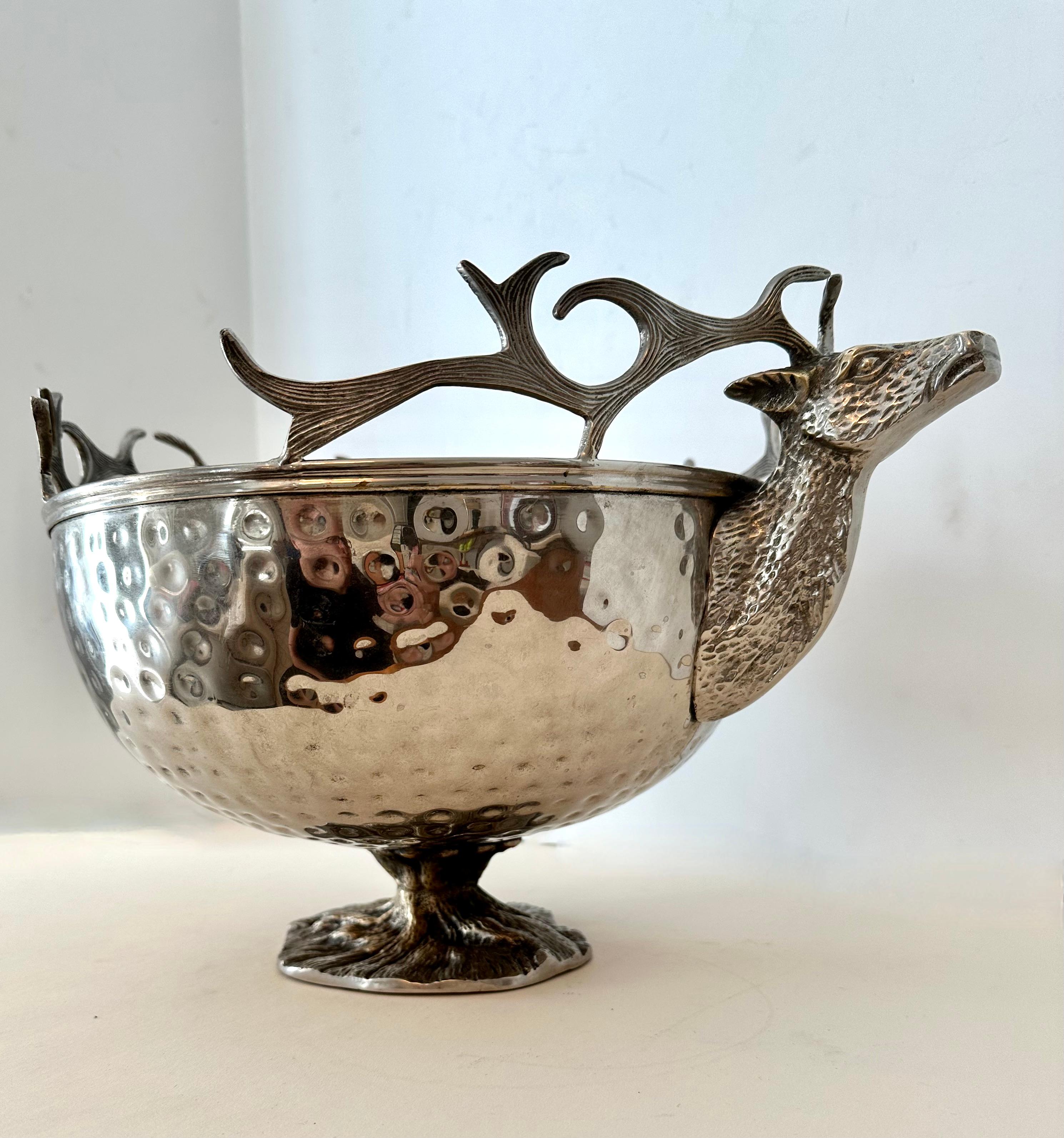 A large silver plate hammered footed bowl with Stag heads for handles. The bowl is in great condition, the stag heads are well designed and have nice detailing - the footed portion is unique as it has the look of an intricate grown tree base.

A