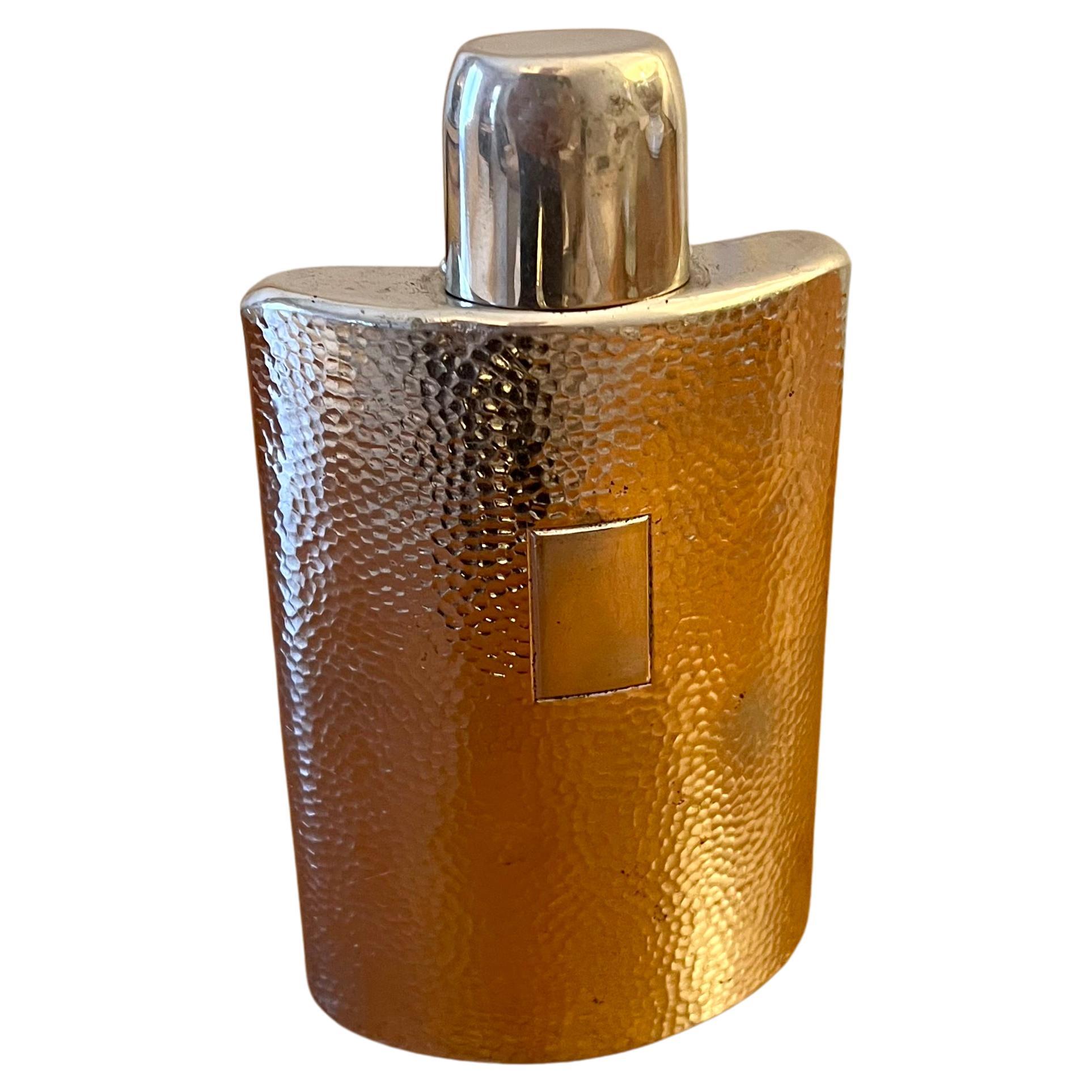 This hammered silver-plate hip flask catches light beautifully. This unique flask has a removable lid that becomes a drinking cup. 

The flask opens with a second stopper. The stopper screws on - the cork which fitted into the opening has worn away