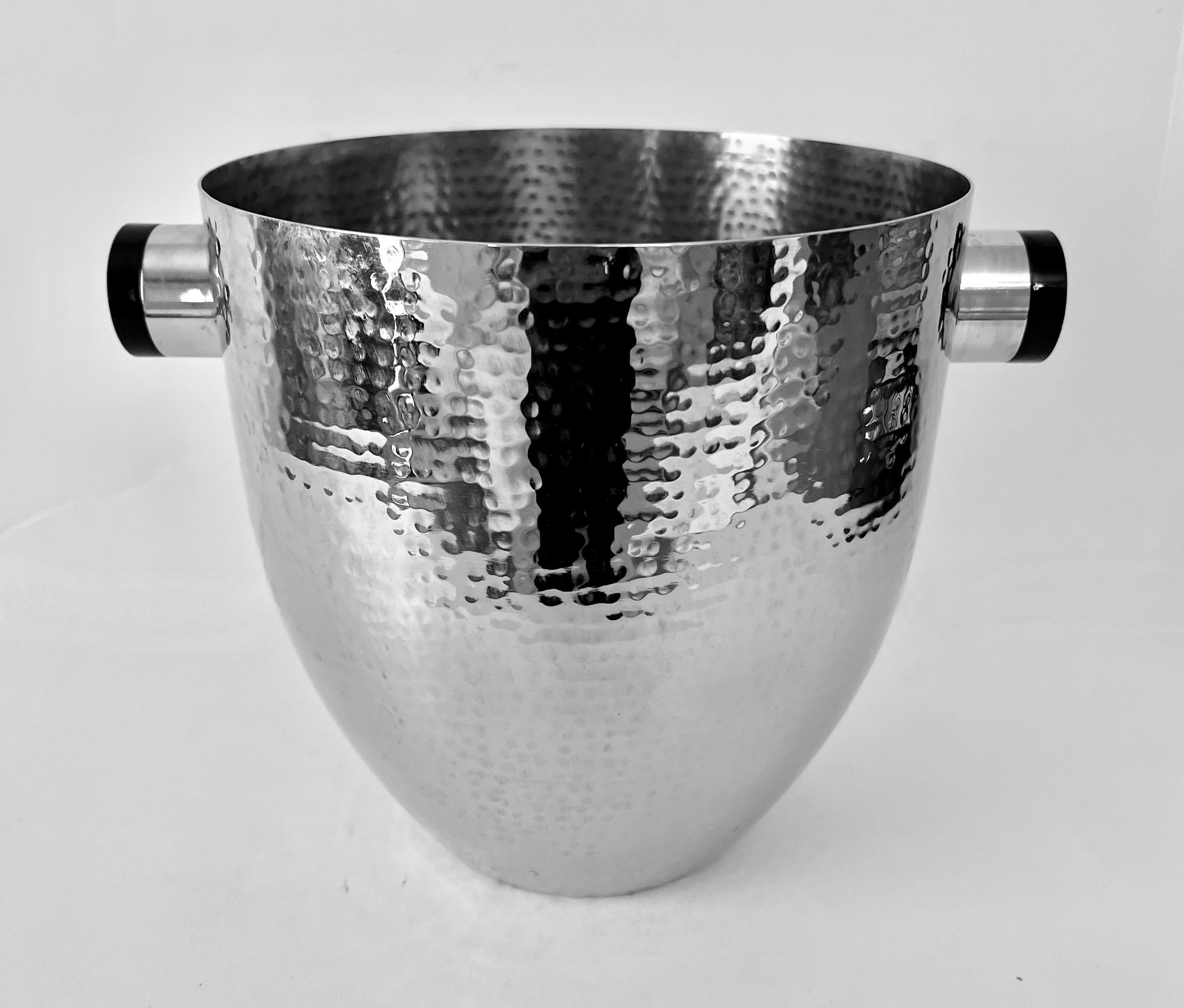 A polished and Hammered Chrome or Silver Champagne /Wine cooler or Ice Bucket.

The piece is in very good condition with unique handle / Cylinders with a black cap of black resin - looks similar to Bakelite.

The size and presence of the bucket make