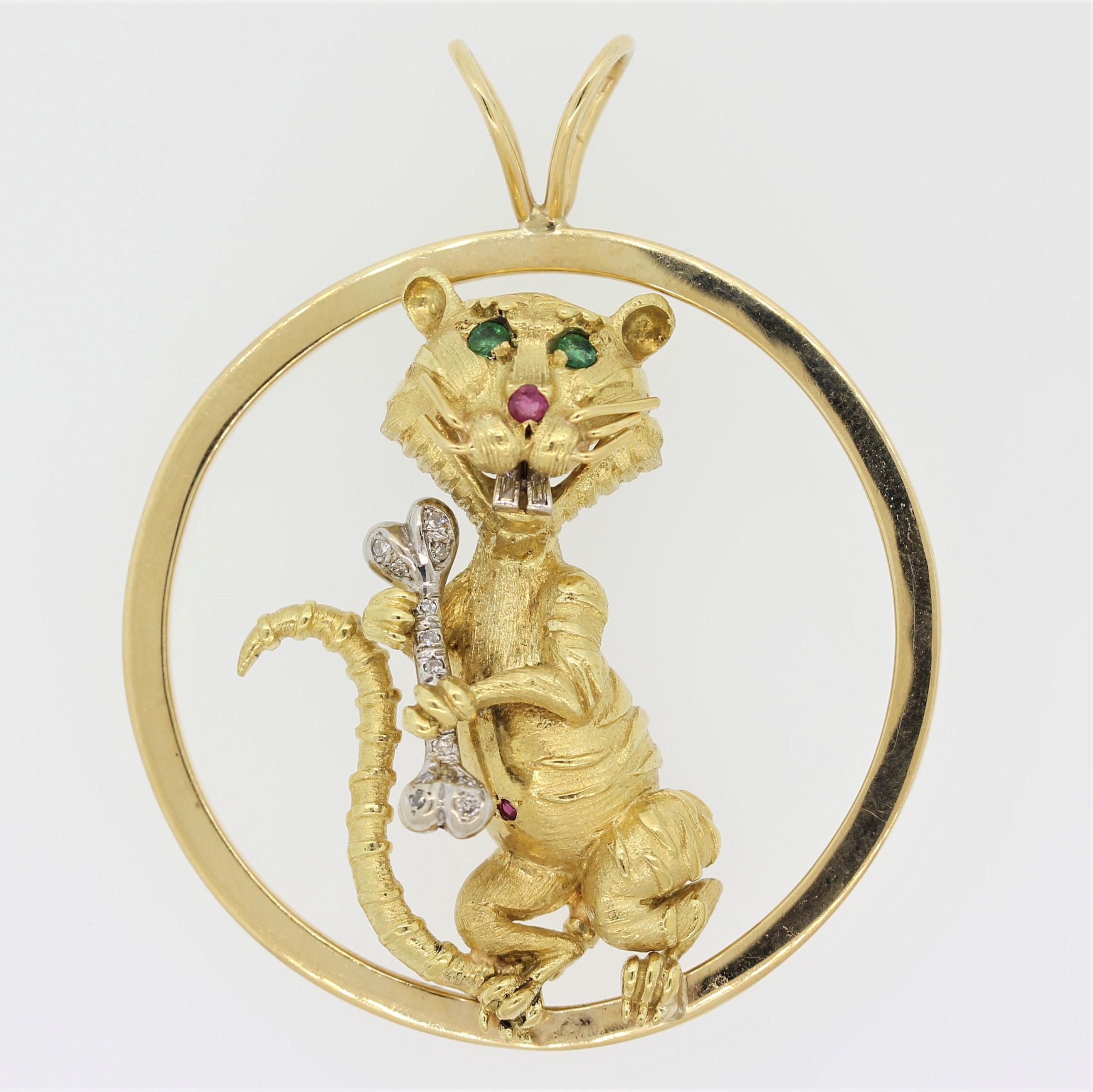 A whimsical pendant from Hammerman Bros. It features a sly alley cat with emerald eyes and a ruby nose holding a diamond studded bone. Its belly button is set with a single ruby and its two buck teeth have diamonds set in them. Made in 18k yellow