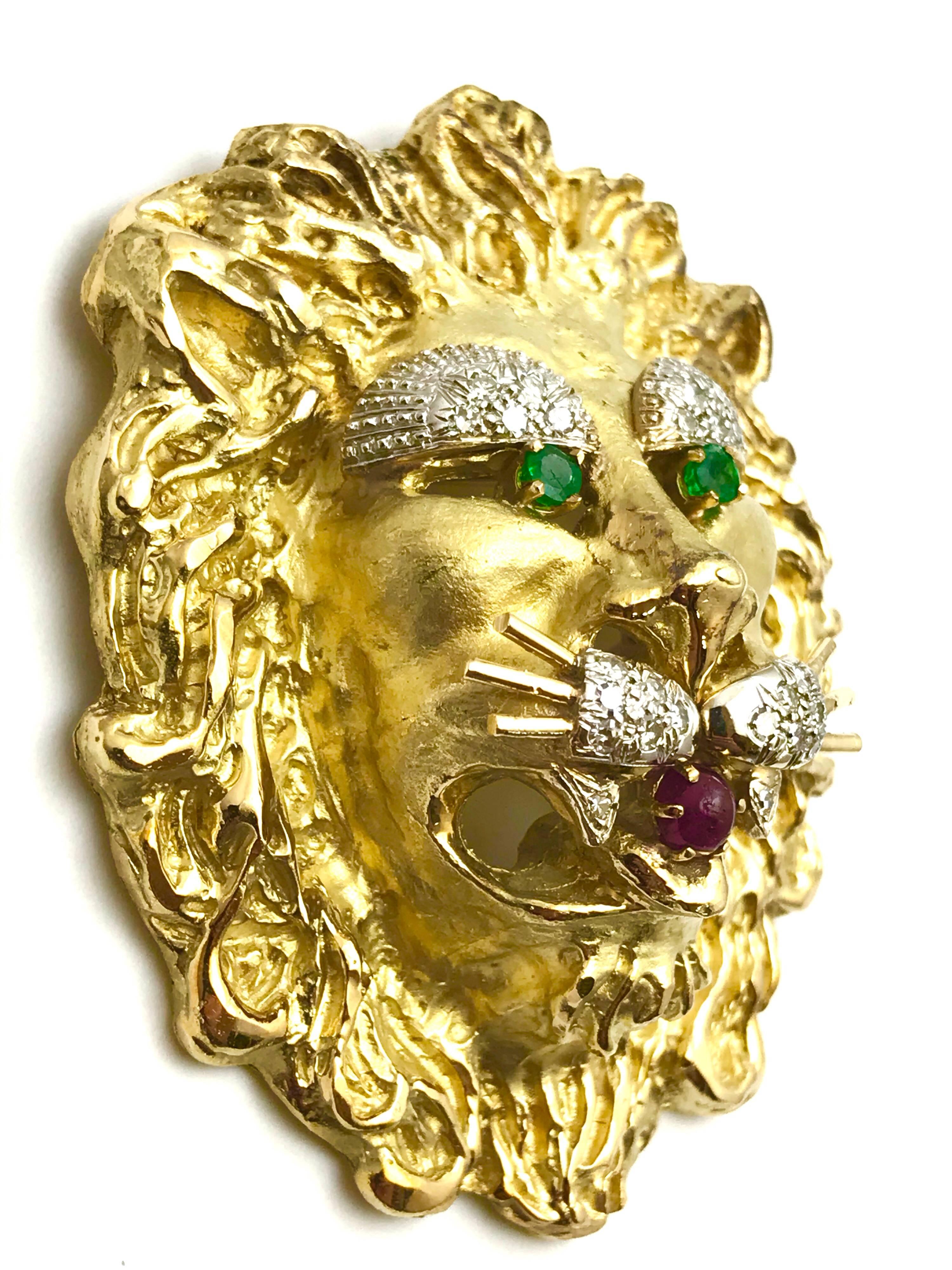 Large 18K yellow gold lion brooch pendant by Hammerman Brothers.  Set with two round cut emeralds, a round cabochon ruby and 24 single cut diamonds.  The lion measures 2 1/2