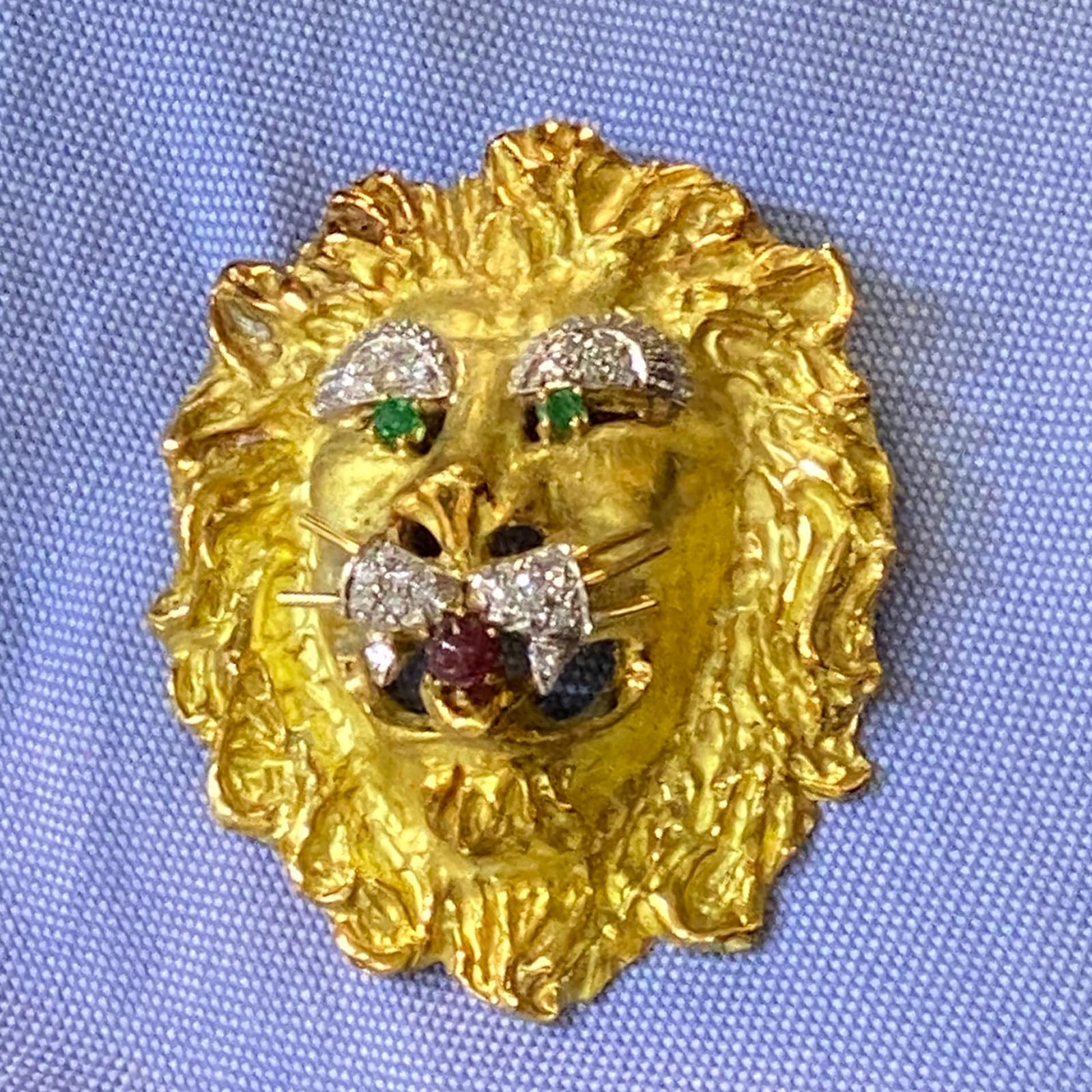 Vintage Lion's Head Pendant/Piin, by Hammerman Brothers, is fashioned in 18 karat yellow gold. The piece can be worn as a pendant or pin, and features diamonds, emerald eyes, and ruby mouth. The 23 round brilliant cut diamonds weigh approximatel .50