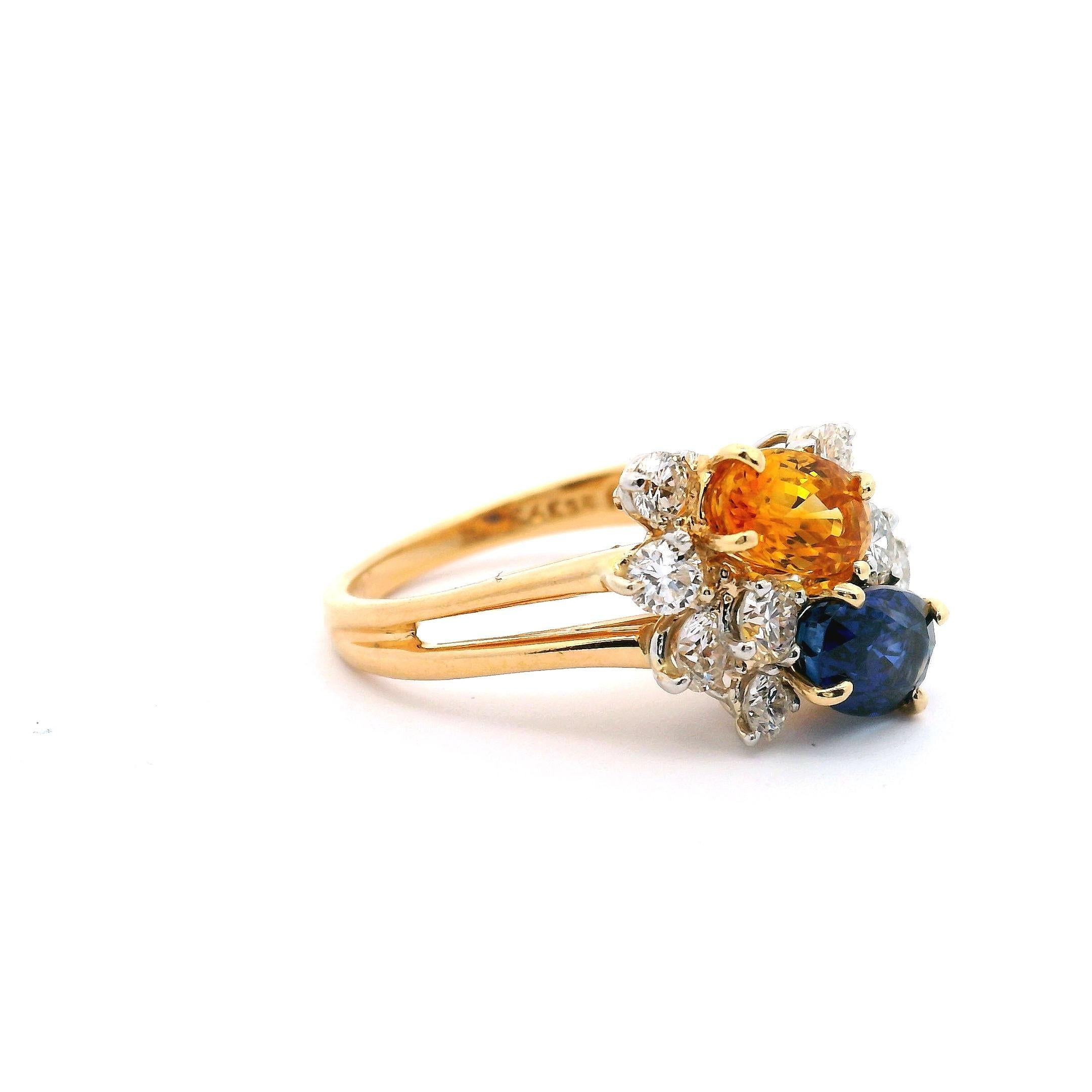 Anello da donna in oro giallo 18kt. a forma di bouquet con uno zaffiro giallo e uno blu. Adornato con cinque diamanti rotondi su ciascun lato degli zaffiri.
Composto da:

Zaffiro blu taglio ovale 1,22ct.
Zaffiro giallo taglio ovale 1,05ct.
10