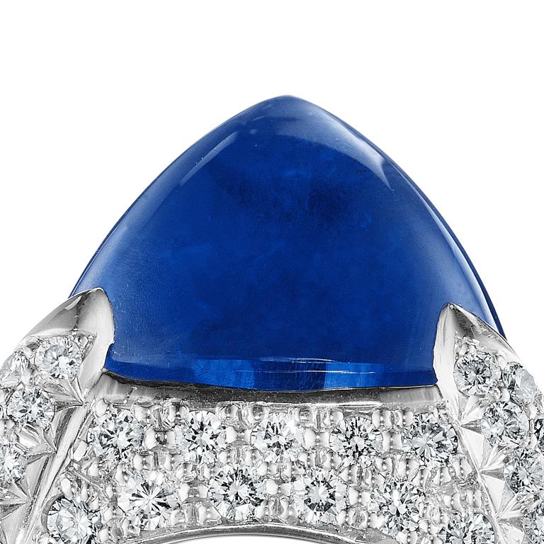 Platinum diamond set ring with a cabochon sugarloaf center Ceylon Sapphire flanked by striking pear shape diamonds. Ceylon is known for its beautifully hued sapphire stones. 

Composition: 1 Ceylon Sapphire weighing 12.44 carats, 15 diamonds, 1.58