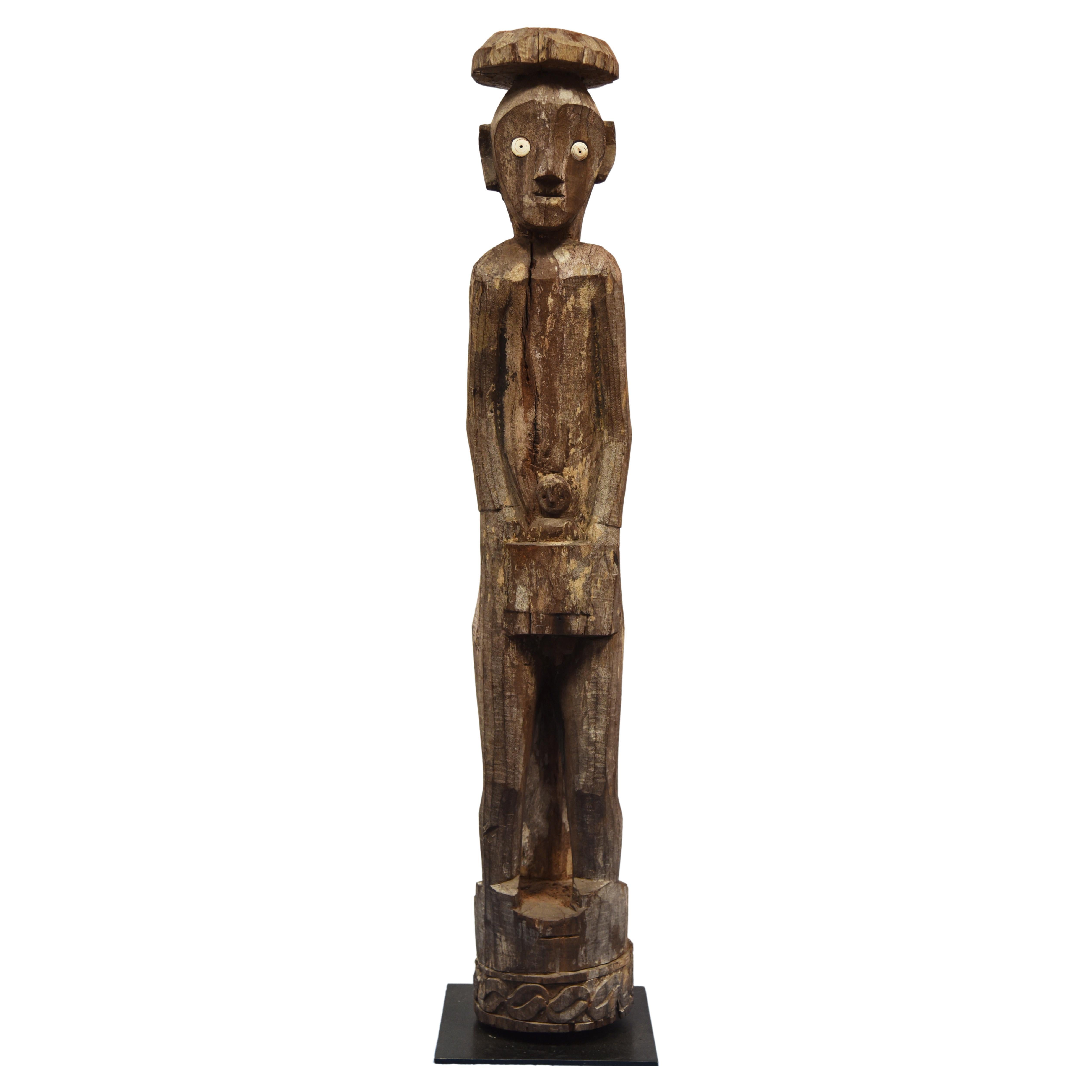 Carved wood figure of MAILE white child with a reptile wrapped around the back of the standing hand-carved wooden figure sculpture. Hampatong carved in Borneo, Indonesia by the Ban Dayak people of the interior rain forest. Hardwood and shell carved