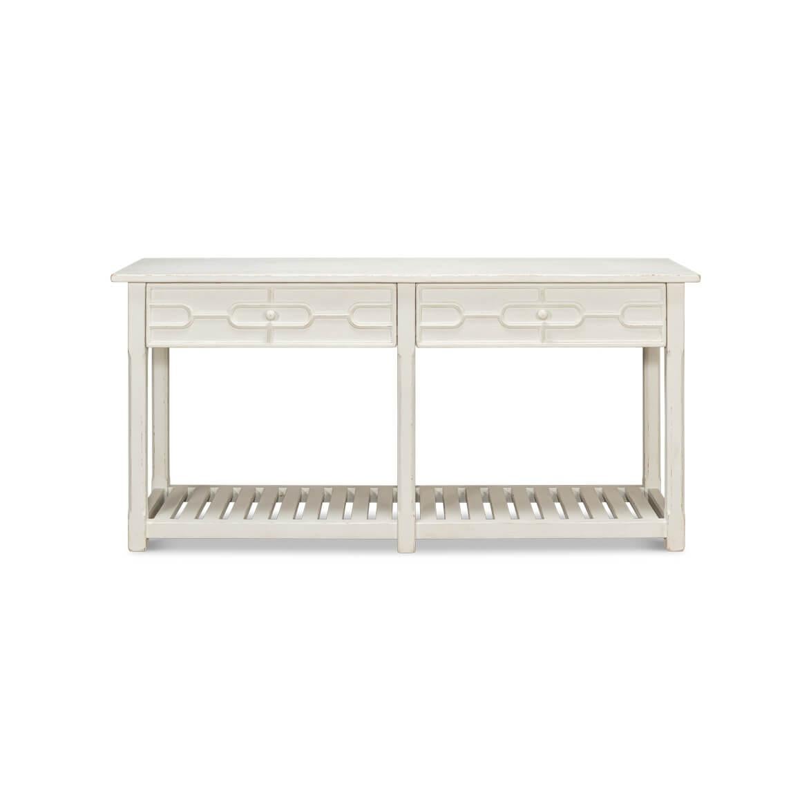 Painted Console Table featuring a rustic country distressed antique white painted finish. It boasts a rectangular top above two wide drawers adorned with blind fret trellis form decoration. The table is raised on six legs with a slatted shelf