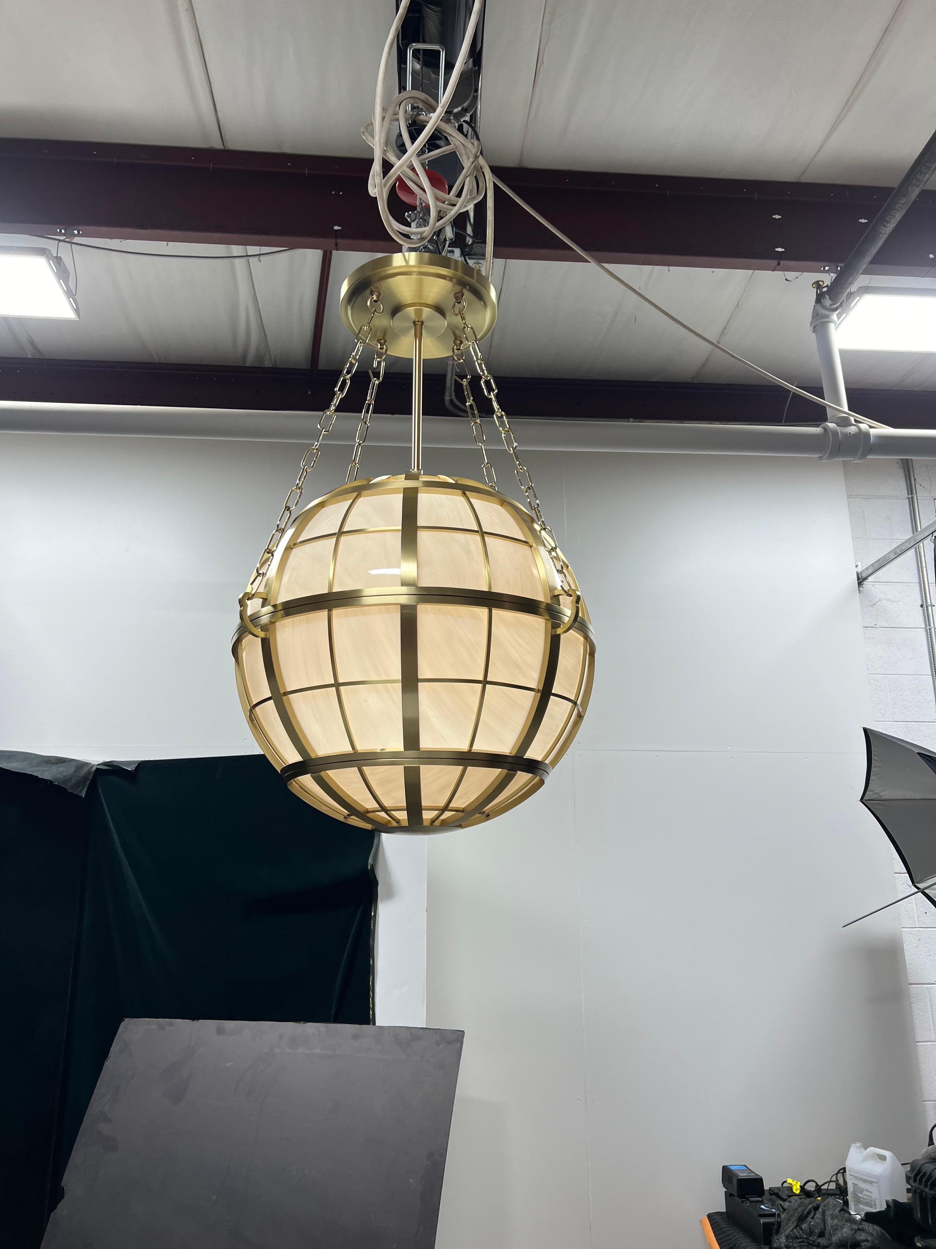 Il ciondolo a forma di globo di Hamptons Roads emana un'aura di opulenza, racchiuso all'interno di sostanziose cinghie intrecciate meticolosamente realizzate in ottone pesante e lucente. Sospeso con grazia da una catena decorativa, il pendente emana
