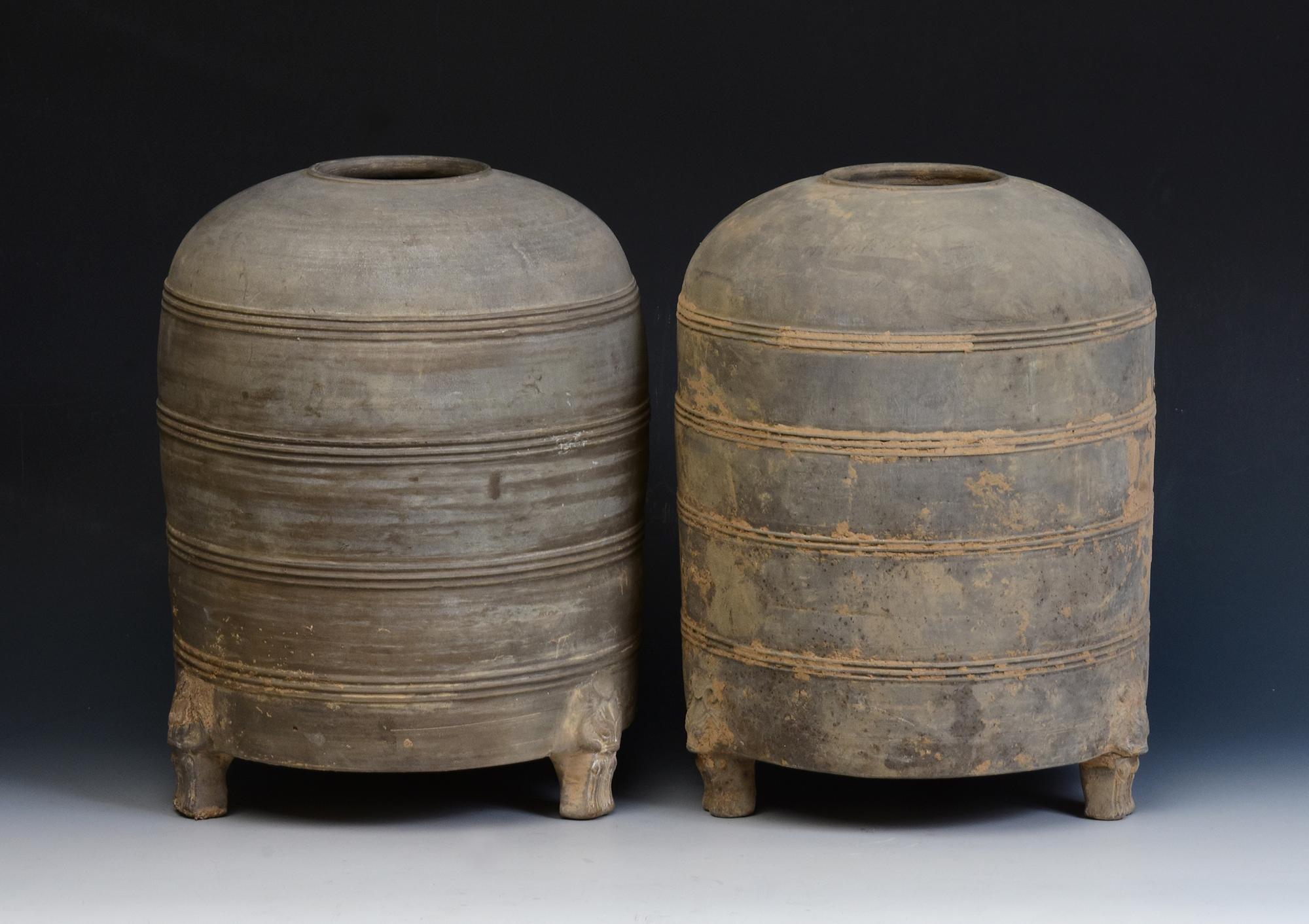 A pair of antique Chinese pottery granary jars with bear-shaped legs, cylindrical shape, decorated with bands of incised lines, and supported by three legs. 

Age: China, Han Dynasty, 206 B.C. - A.D. 220
Size: Height 32 C.M. / Width 23.5 - 24