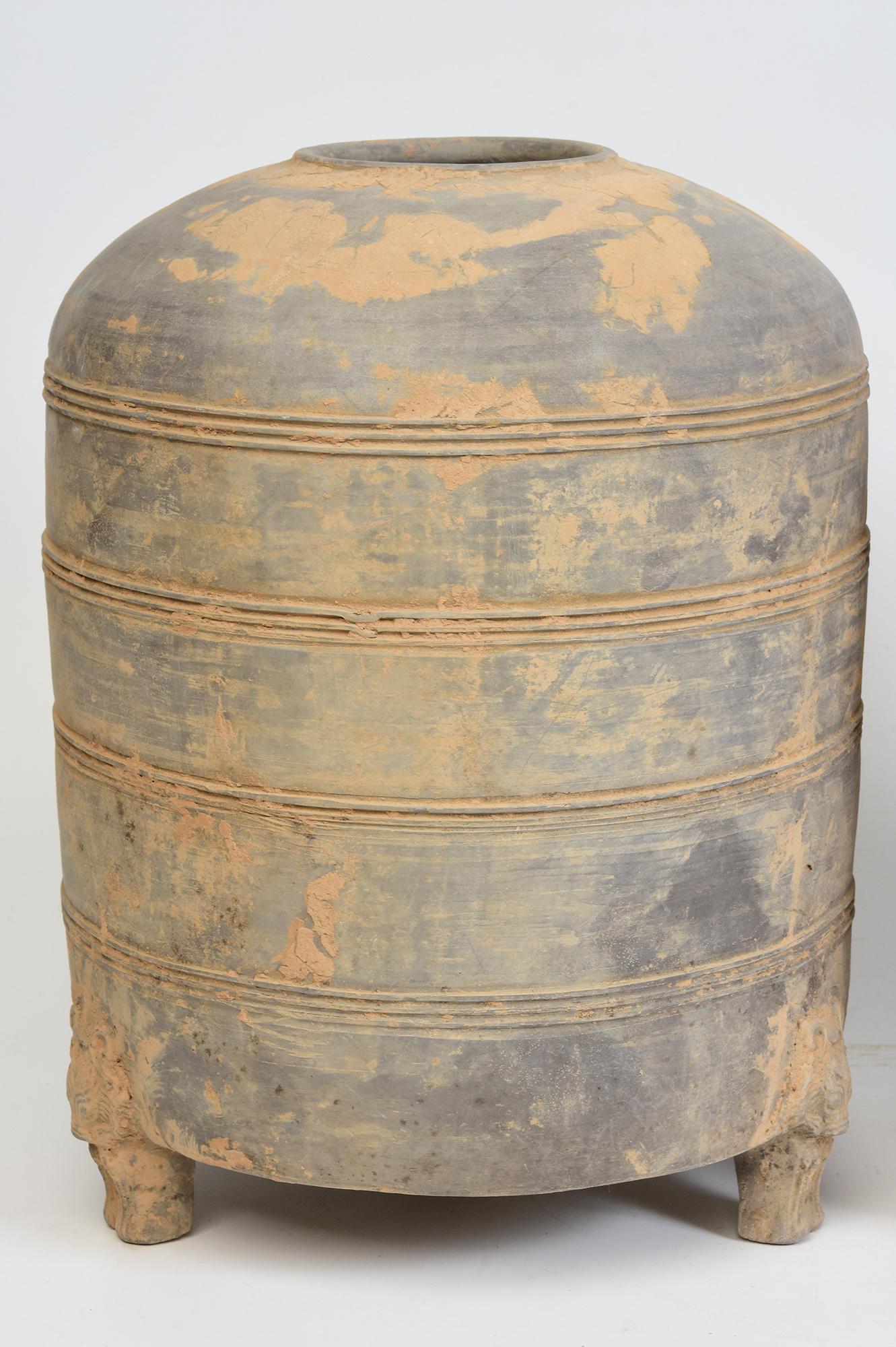 A pair of antique Chinese pottery granary jars with bear-shaped legs, cylindrical shape, decorated with bands of incised lines, and supported by three legs.

Age: China, Han Dynasty, 206 B.C. - A.D. 220
Size: Height 31 C.M. / Width 23