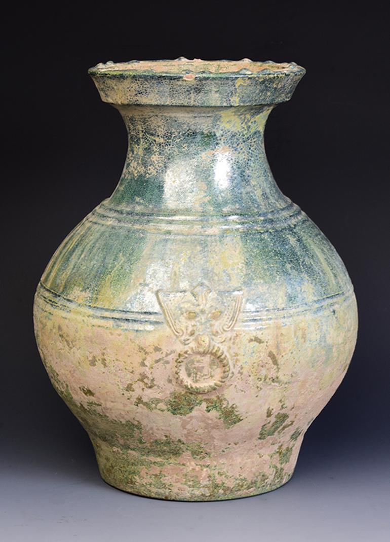 Antique Chinese green glazed pottery Hu jar with silvery surface decorated with bands of raised lines and a pair of monster masks on the shoulder.

Lead glaze with copper is the main colorant used in Han period to produce green glaze. Greenware