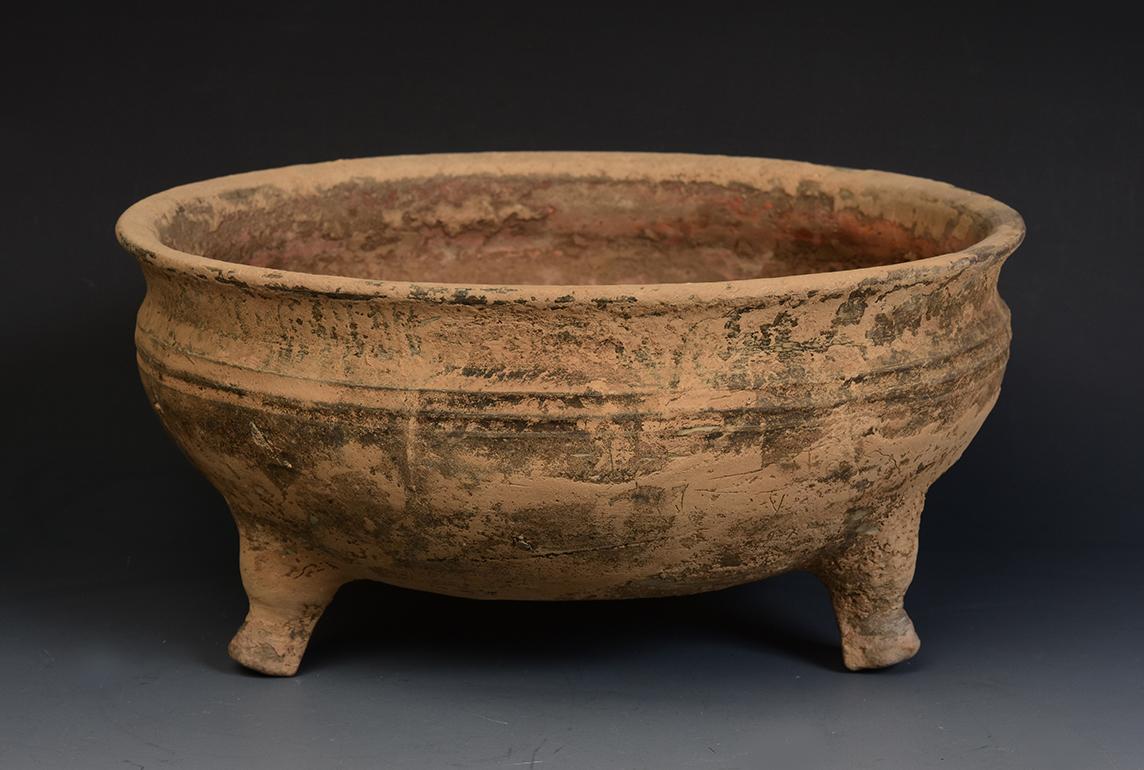 Chinese pottery bowl support by three legs.

Age: Chinese, Han Dynasty, B.C. 206 - A.D. 220
Size: Diameter 23.7 C.M. / Thickness 11.7 C.M.
Condition: Well-preserved old burial condition overall with some amount of soil adhering (some abrasions and