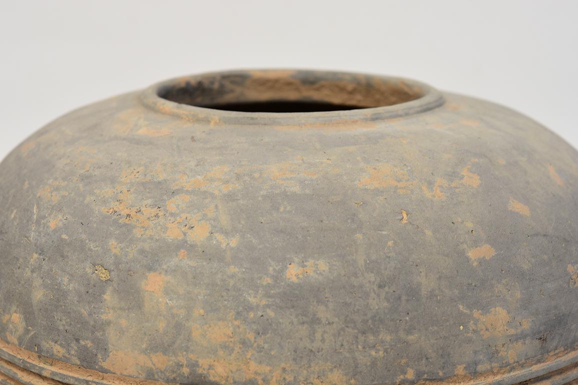 Chinese pottery granary jar, with cylindrical shape, decorated with bands of incised lines, and supported by three legs. 

Age: China, Han Dynasty, 206 B.C. - A.D. 220
Size: height 27.8 cm / width 19.8 cm
Condition: Well-preserved old burial