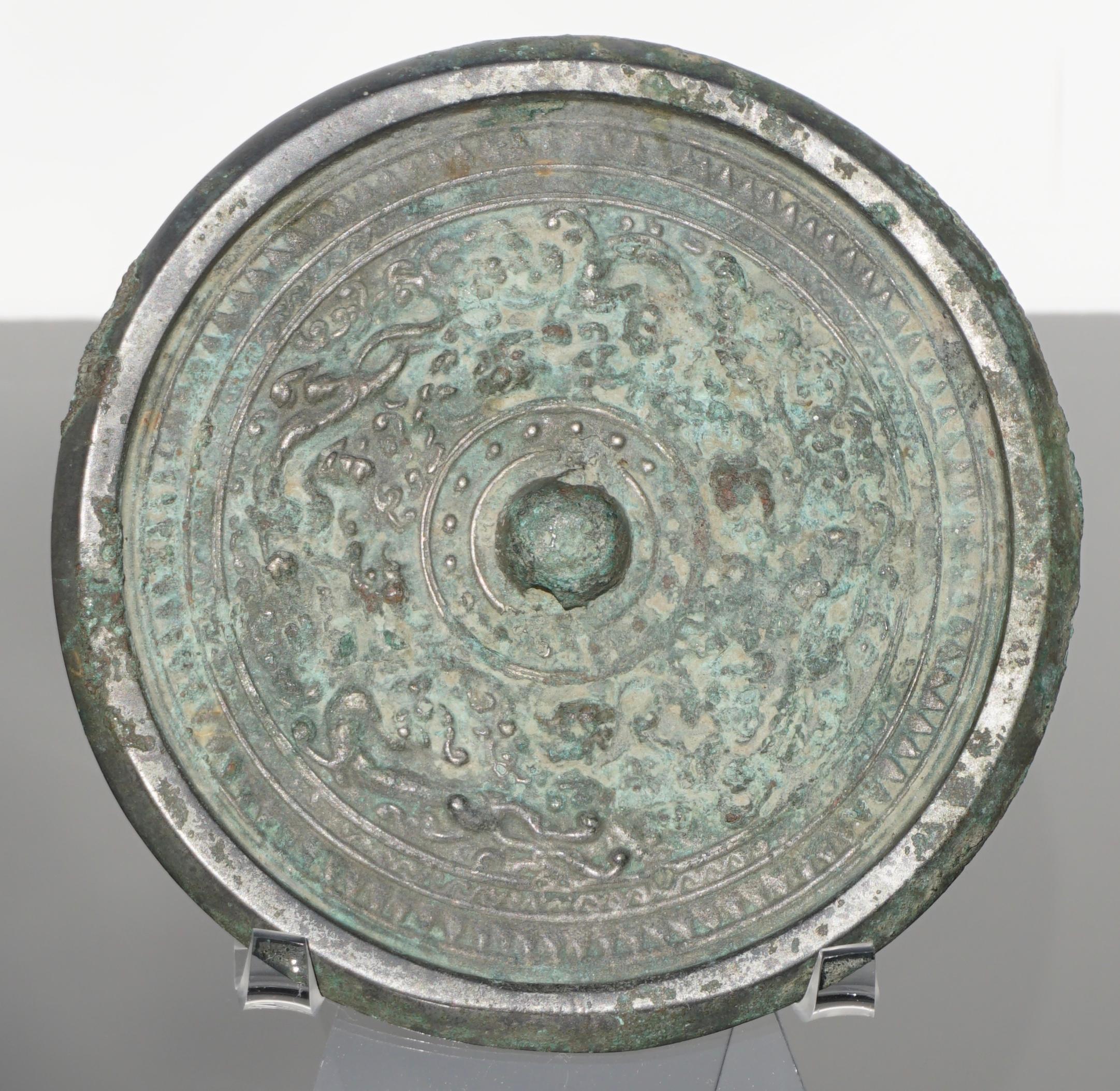East Asia, China, 
Han Dynasty, ca. 206 BCE to 220 CE. 

A bronze mirror with cast motifs and a raised, nub-like handle. The handle is pierced through laterally, allowing the mirror to be worn. The cast motifs include flowing floral motifs and