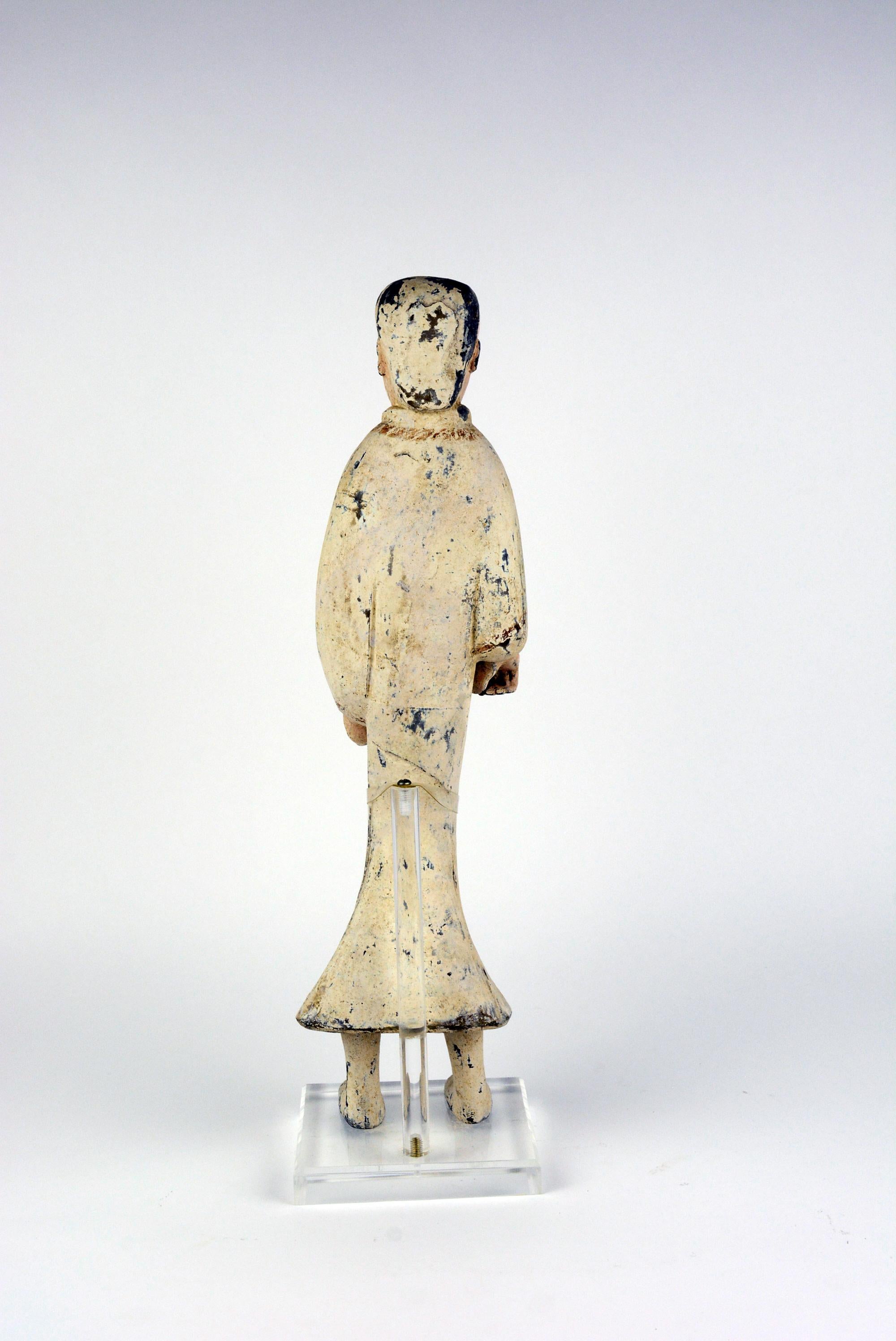 This is a Han Dynasty unglazed dark pottery female attendant dressed in a white robe with straps of red pigment on the collar. From Xian. She is on a stand. The measurements reflect the stand width and depth and her height includes .75 inch for the