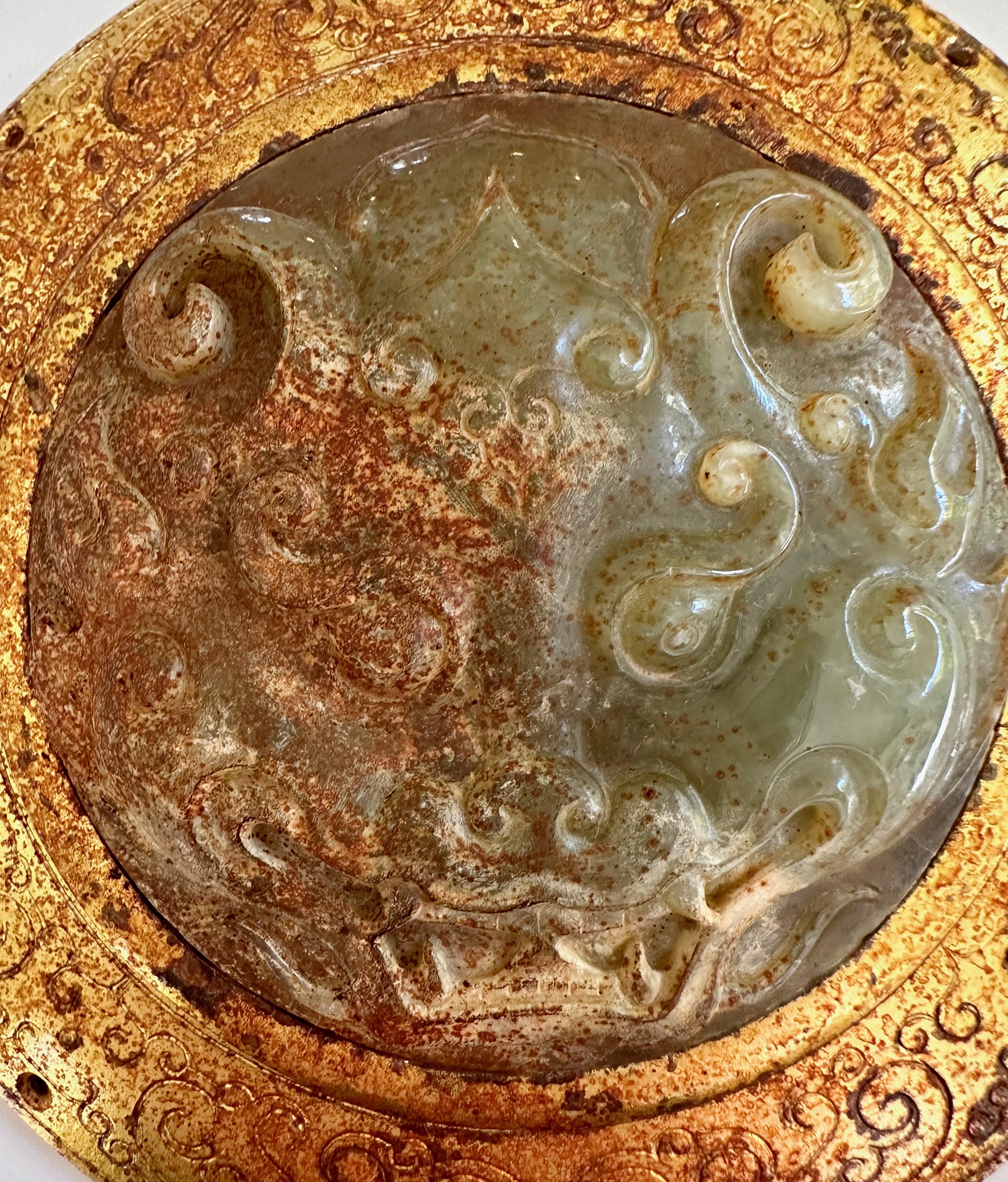 Sumptuously mounted carved jade pendant decorated with Taotie mask, with incised gilt bronze fitting, Han Dynasty (206 B.C. to 220 A.D.).

This piece, which has four holes in the gilt bronze mounting and would likely have been worn on the robe of an