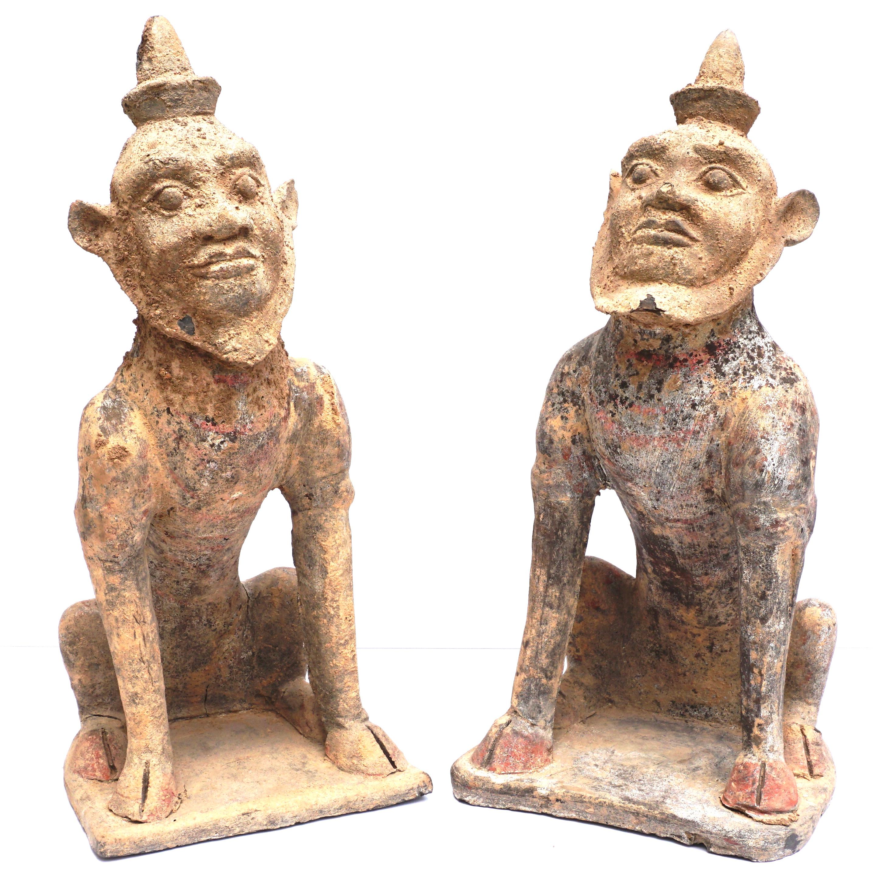 Chinese, Tang Dynasty (618 AD to 906 AD) 
A pair of semi-human earth spirit figures seated on their haunches with cloven hooves planted firmly on the base. Both wearing conical mandarin style hats, their bearded face peering upward with a placid