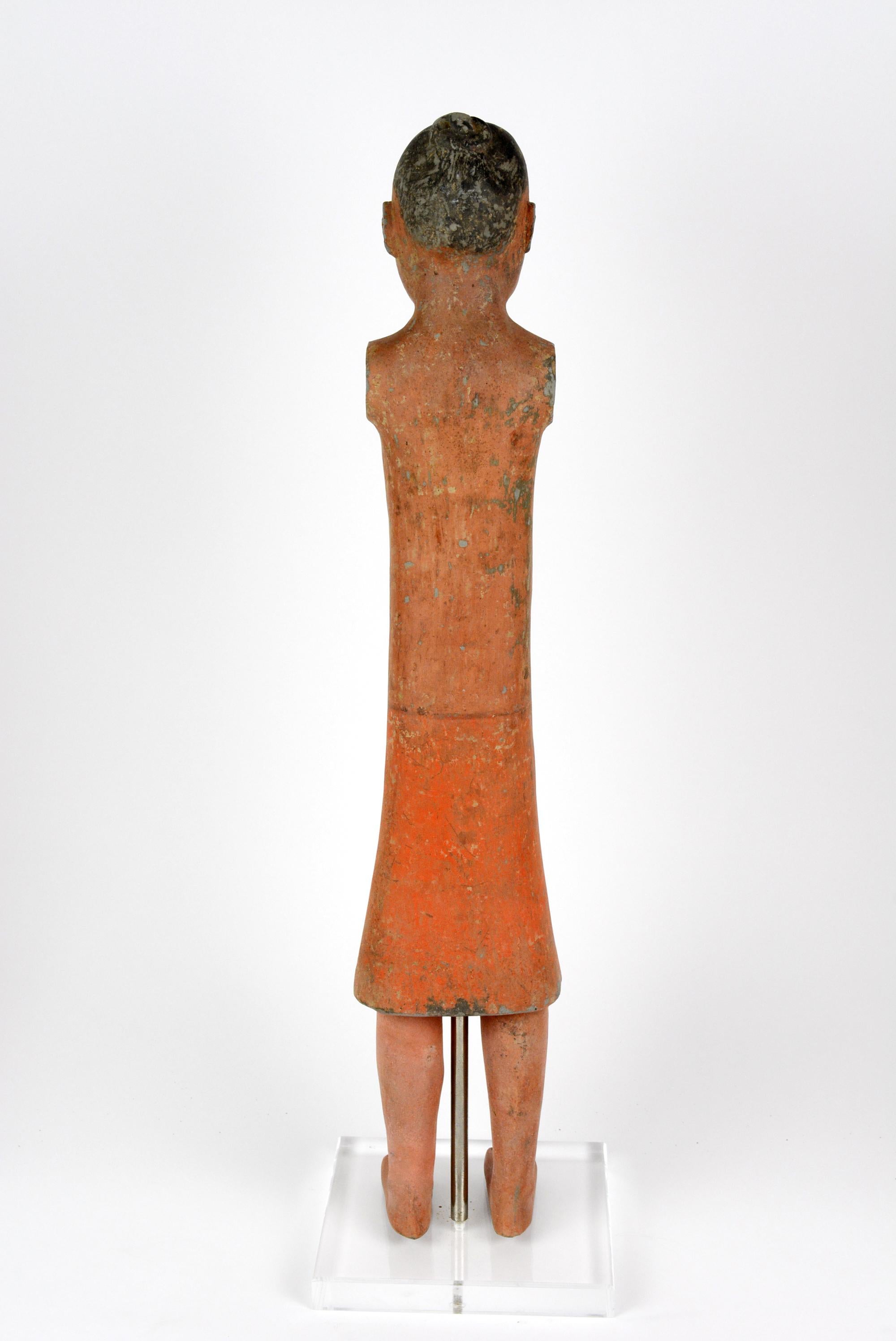 This Han pottery figure of a foot soldier is molded and engraved with facial details. It has been fired at high temperatures. The color pigments are painted on after cooling. This is made of dark pottery and is from Xian. The figure is on a stand