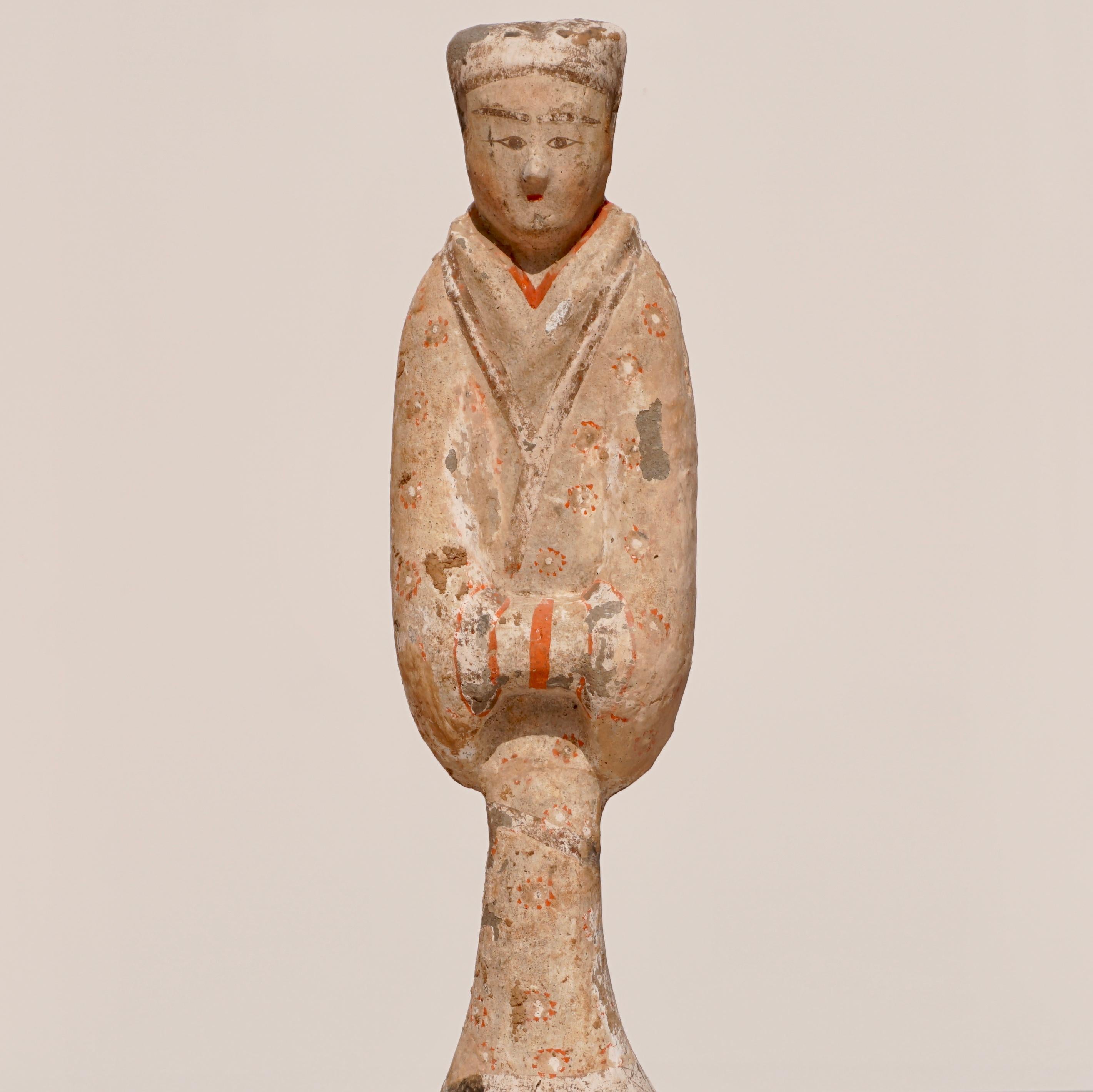 A tall Terracotta sculpture of a court lady figure dressed in flowing robe painted in cream with orange flowers and highlights. The face with piercing eyes and long eyelashes and long hair tied in proper fashion of the Han Dynasty. A proportioned 18