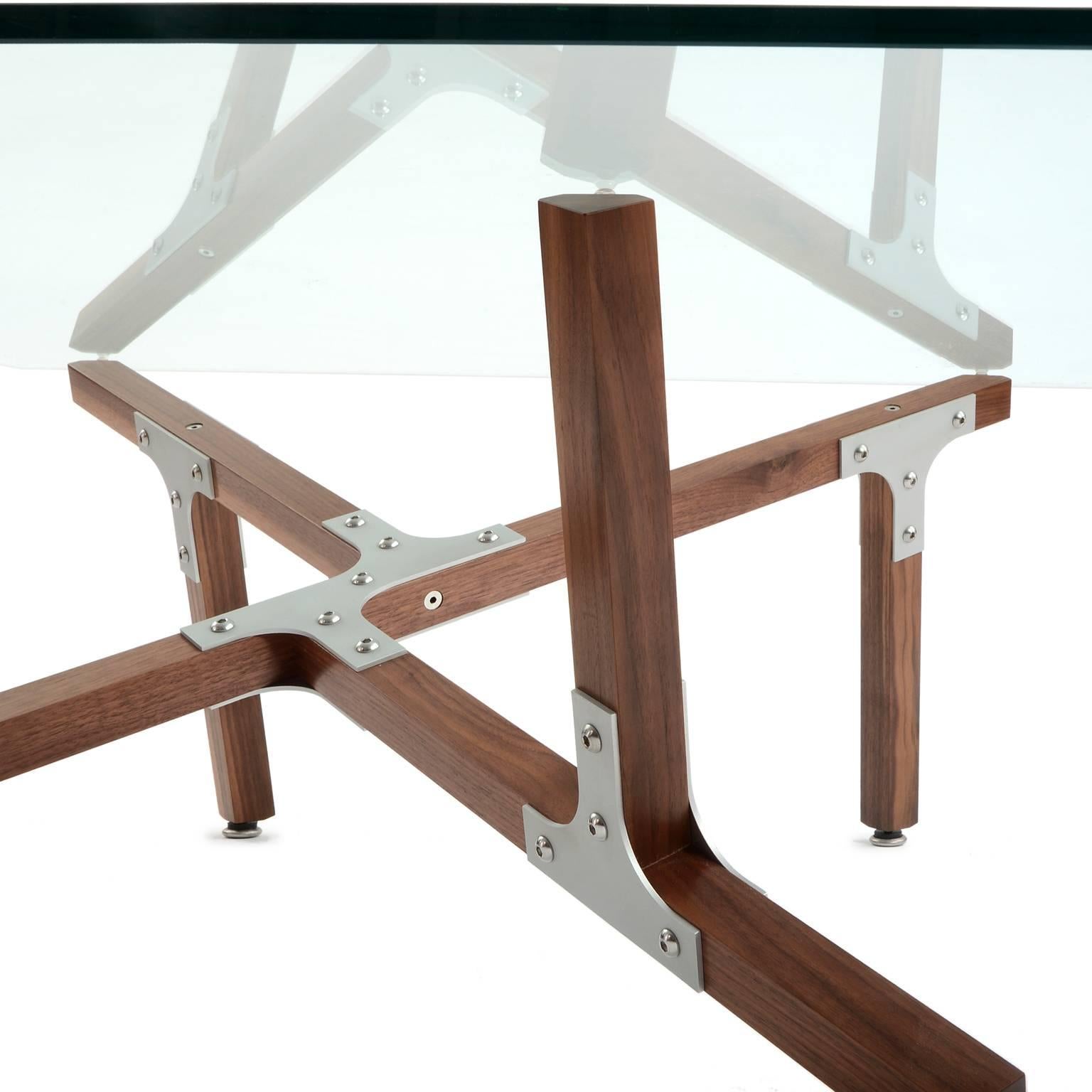 La table basse Hana de Peter Harrison réunit des carrés de noyer massif et des supports industriels en aluminium. La base est semi-symétrique, avec les mêmes éléments pointant vers le haut et vers le bas, mais ces éléments atteignent le sommet en