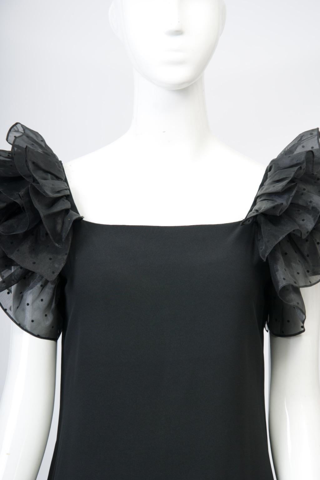 Vestido negro vintage Hanae Mori de los años 80, de crepé negro, ceñido al cuerpo, con escote cuadrado y falda recta hasta la rodilla con abertura trasera. El interés especial procede de las mangas con volantes en los hombros, compuestas por cuatro