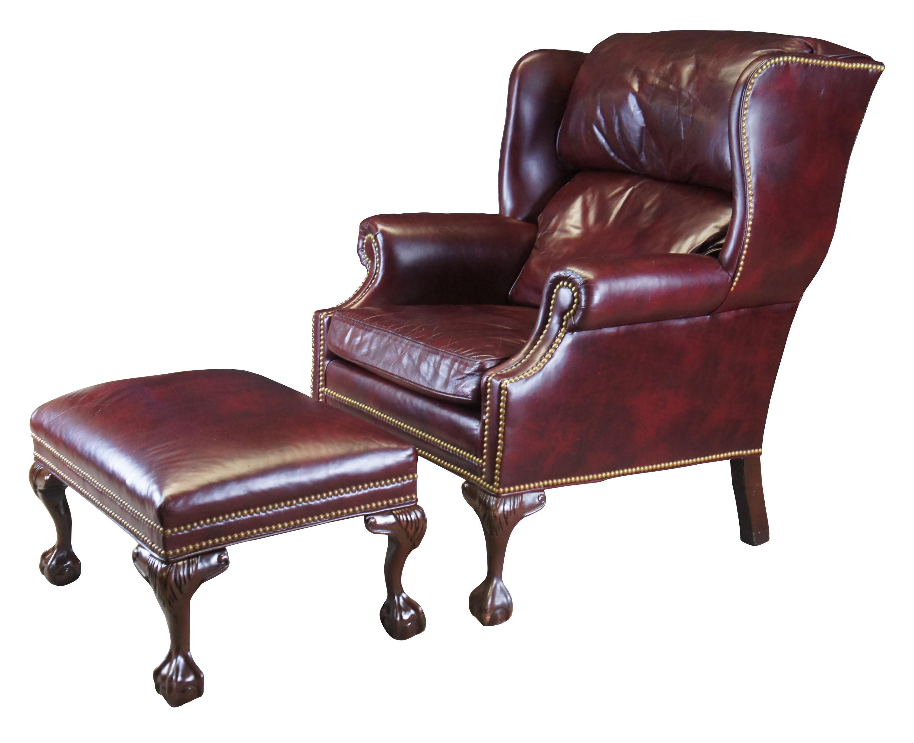 An eye catching wingback chair and ottoman by Hancock & Moore, circa last quarter 20th century.  Inspired by classic English Georgian styling.  Features a hooded back with rolled arms and brass nail head trim.  The chair is supported by carved