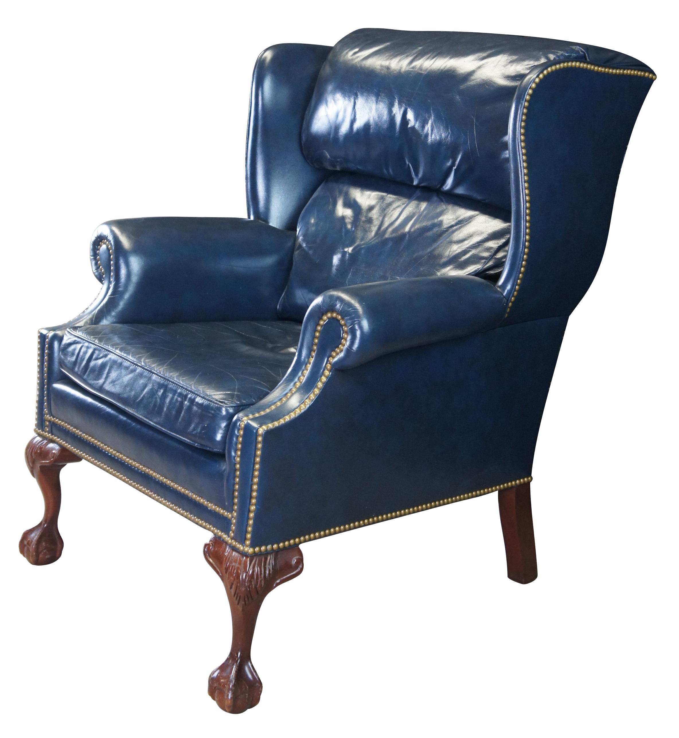 An eye catching wingback chair by Hancock & Moore, circa last quarter 20th century.  Inspired by classic English Georgian styling.  Features a hooded back with rolled arms and brass nail head trim.  The chair is supported by carved mahogany ball and