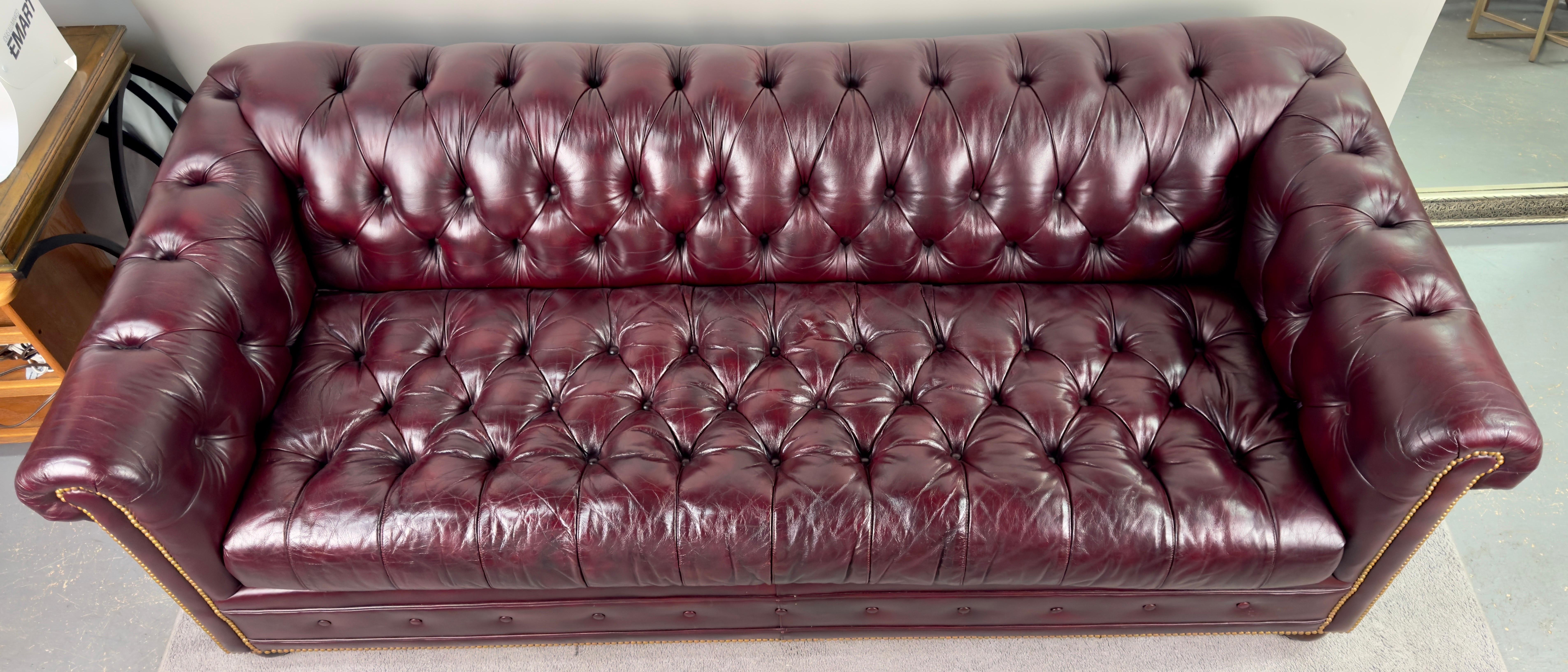 An English Chesterfield style leather sofa by Hancock & Moore, hailing from the renowned workshop in Hickory, North Carolina. This opulent sofa exudes elegance with its rich Williamsburg cranberry hue, reminiscent of traditional luxury.

Adorned