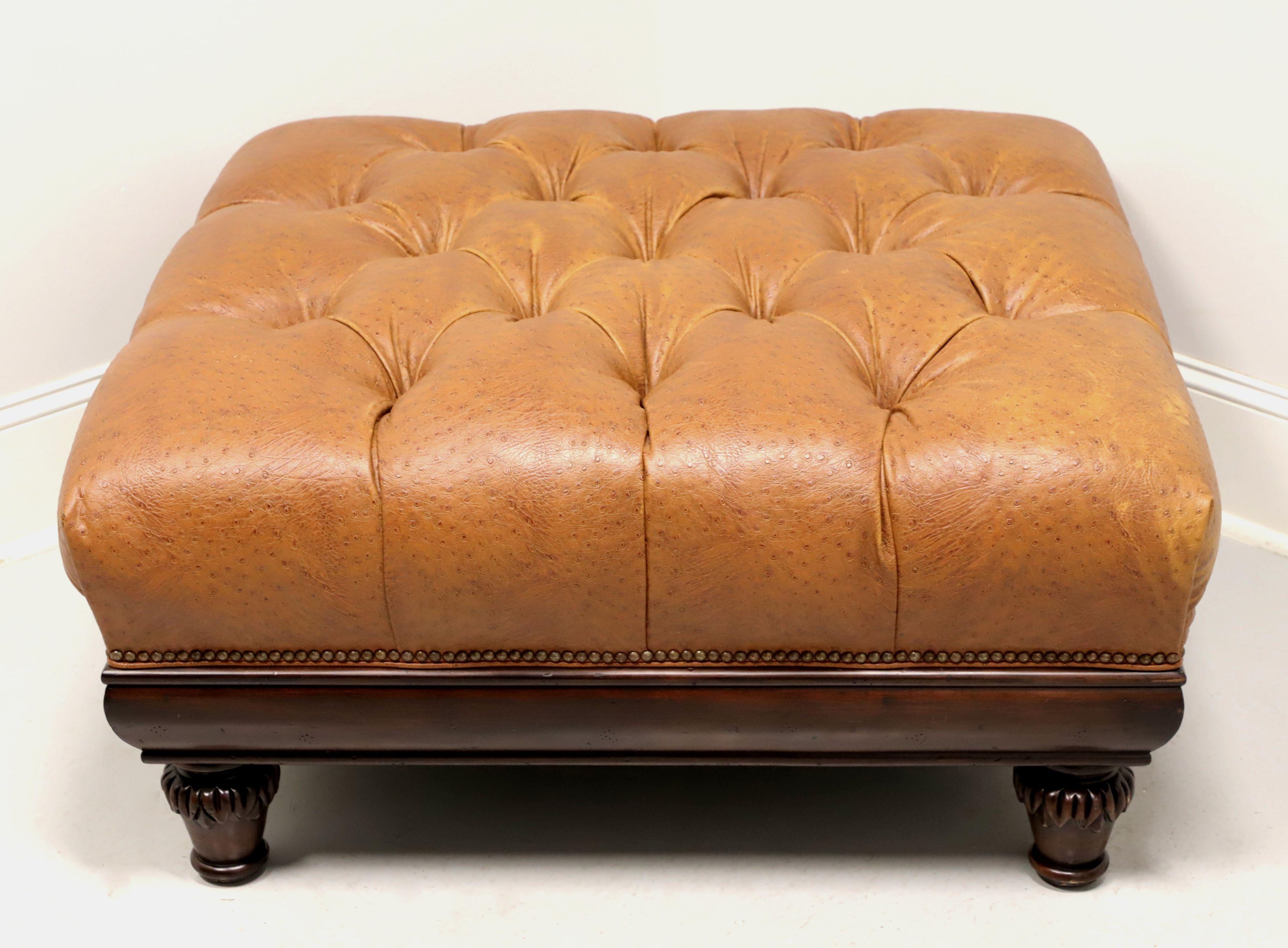 A square leather ottoman in the Regency style by Hancock & Moore. Distressed walnut frame, caramel color ostrich leather, button tufted, brass nailhead trim, crown molding like apron and decoratively carved turnip feet. Made in North Carolina, USA,