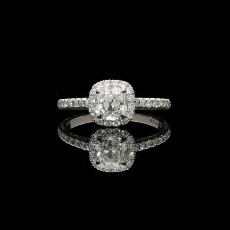 A charming old cut diamond and platinum cluster ring by Hancocks, centred on a beautiful cushion shaped old mine cut diamond weighing 0.90 carats and of J colour and VS1 clarity, claw set within a diamond halo surround between fine diamond-set