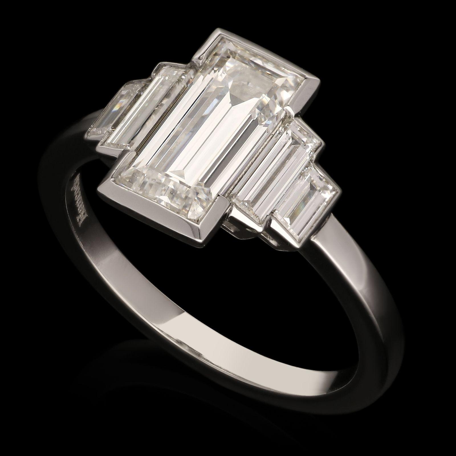 A stunning baguette-cut diamond ring by Hancocks, centred on an elegant, elongated emerald-cut diamond weighing 1.54cts and of F colour and SI1 clarity in a partial rub over setting between shoulders of two stepped baguette-cut diamonds also in