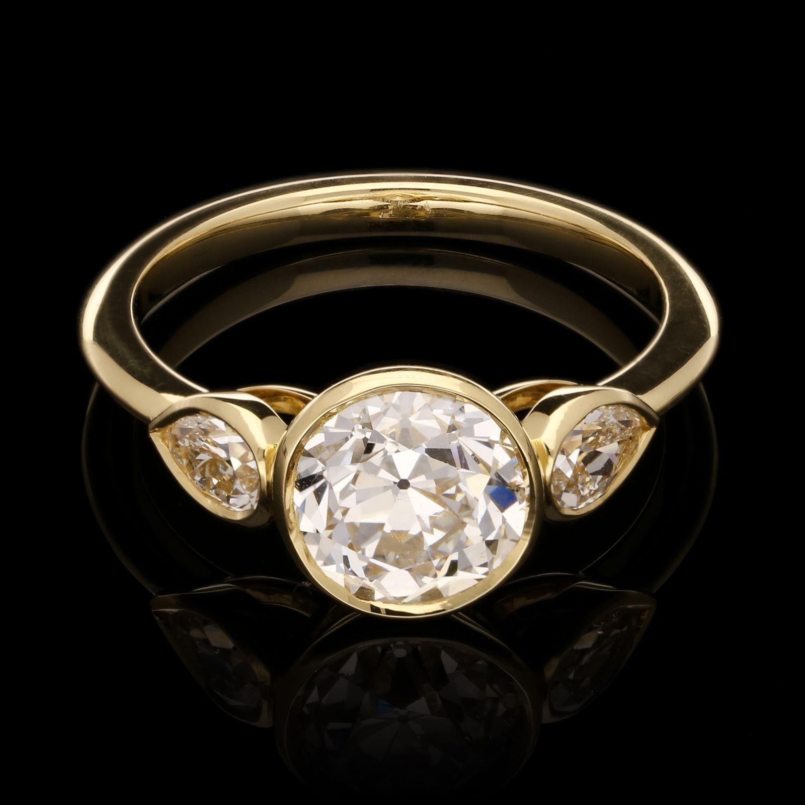 An elegant old cut diamond ring by Hancocks set to the centre with a beautiful old European brilliant cut diamond weighing 1.77ct and of F colour and SI2 clarity between pear shaped diamond shoulders, all in a finely crafted handmade 18ct yellow