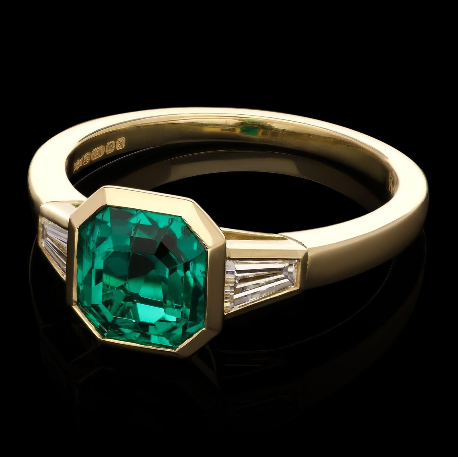 A beautiful emerald and diamond ring by Hancocks, centred on a lovely rich and deeply saturated emerald-cut Colombian emerald weighing 1.83cts rub over set in 18ct yellow gold between elegant tapering shoulders each set with a tapered baguette cut