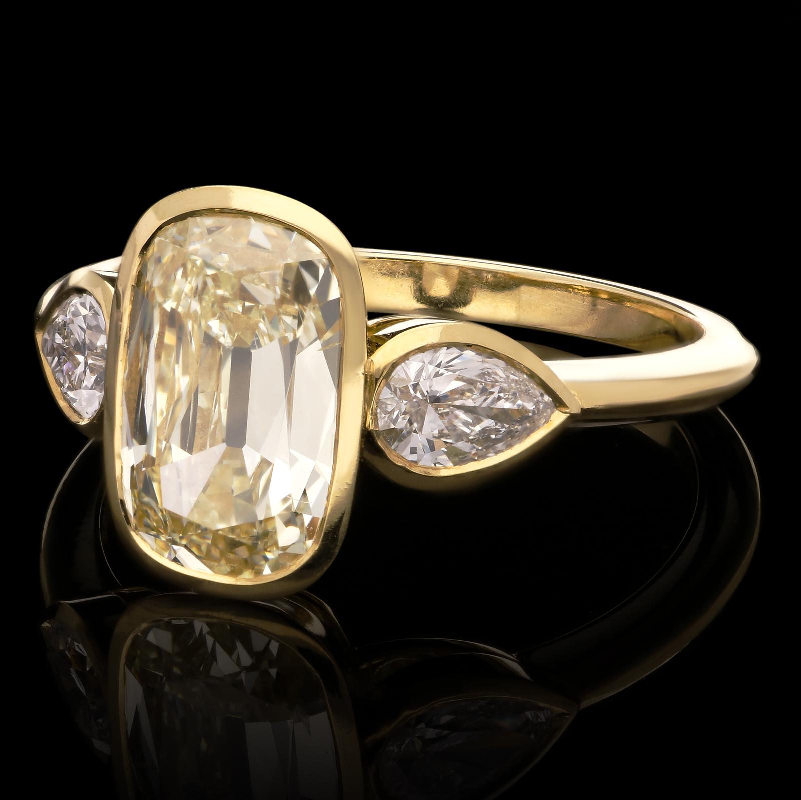 A beautiful contemporary gold and diamond ring by Hancocks, centred with an elongated cushion shaped brilliant cut diamond weighing 2.02ct and of warm pale yellow colour and SI1 clarity, in a fine rub-over setting of 18ct yellow gold, set vertically