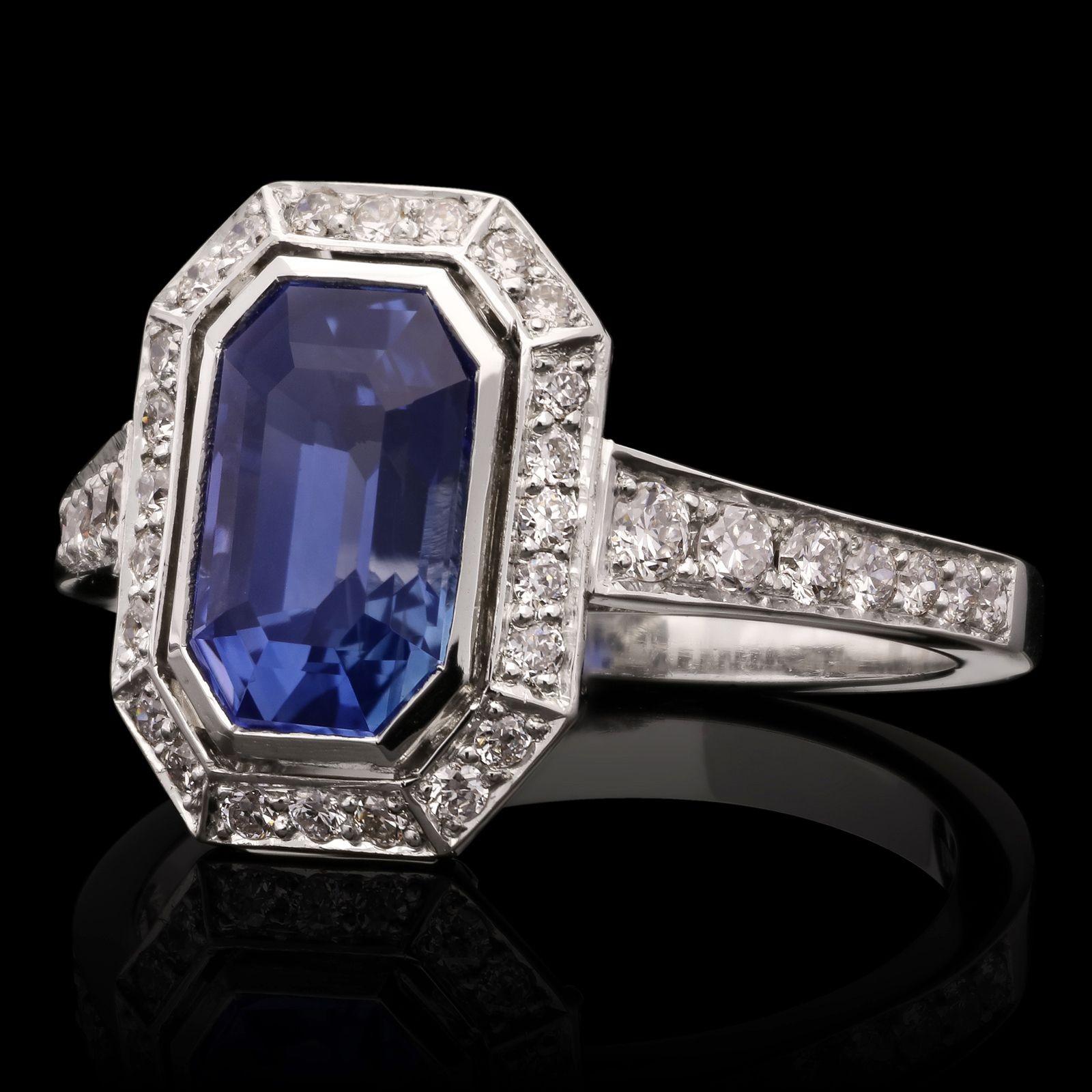 An elegant sapphire and diamond cluster ring by Hancocks, centred with a beautiful octagonal step-cut Madagascar sapphire weighing 2.15cts rub over set within a well-proportioned geometric cluster surround of round brilliant cut diamonds in channel