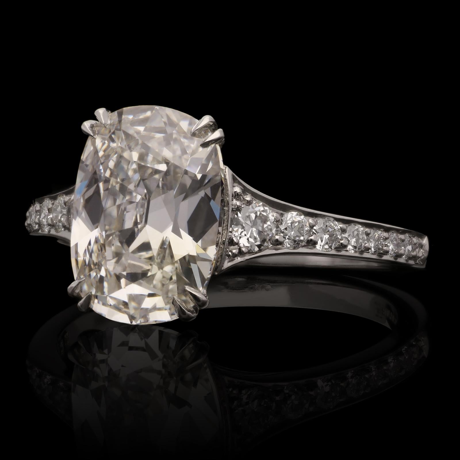 A beautiful cushion shaped diamond ring by Hancocks, centred with a bright and lively old brilliant cut diamond weighing 2.55cts and of F colour and VVS2 clarity, set in platinum with V shaped double corner claws to a diamond-set gallery, between