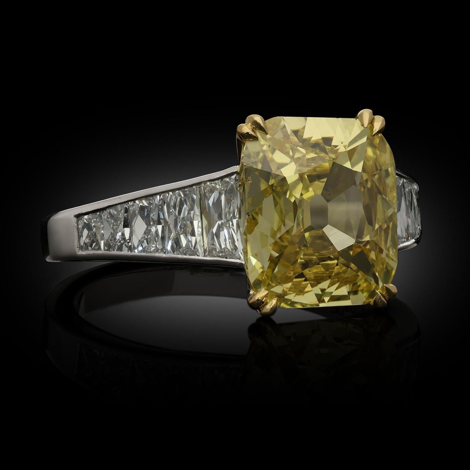A beautiful fancy intense yellow diamond and diamond ring by Hancocks, centred with an old cushion cut diamond weighing 2.56cts and of fancy intense yellow colour and I1 clarity claw set in 18ct yellow gold between elegantly tapering shoulders
