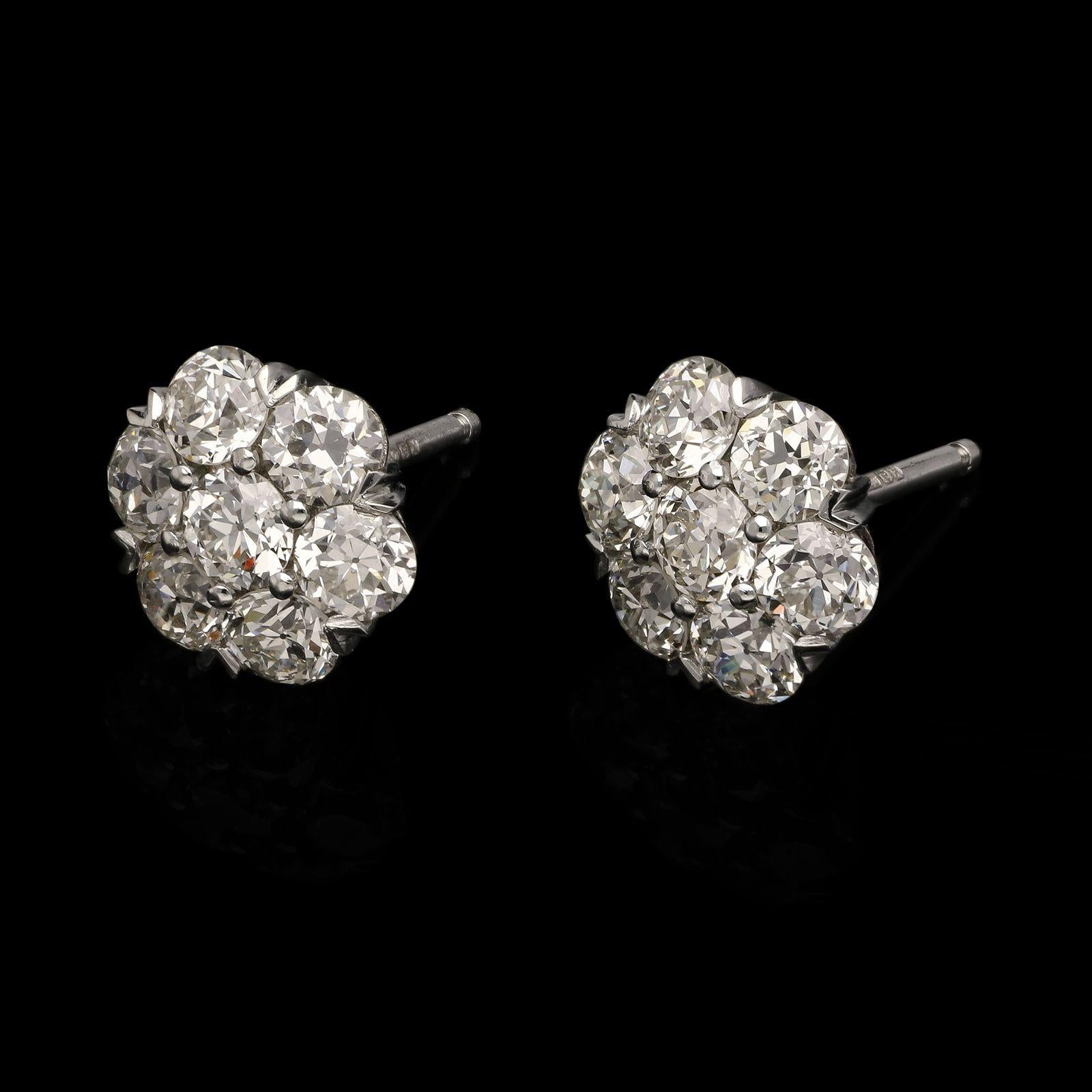 A beautiful and classic pair of diamond cluster earrings by Hancocks, each set to the centre with a bright and lively old European brilliant cut diamond surrounded by six others, the diamonds weighing 2.80cts in total and all set in platinum claw
