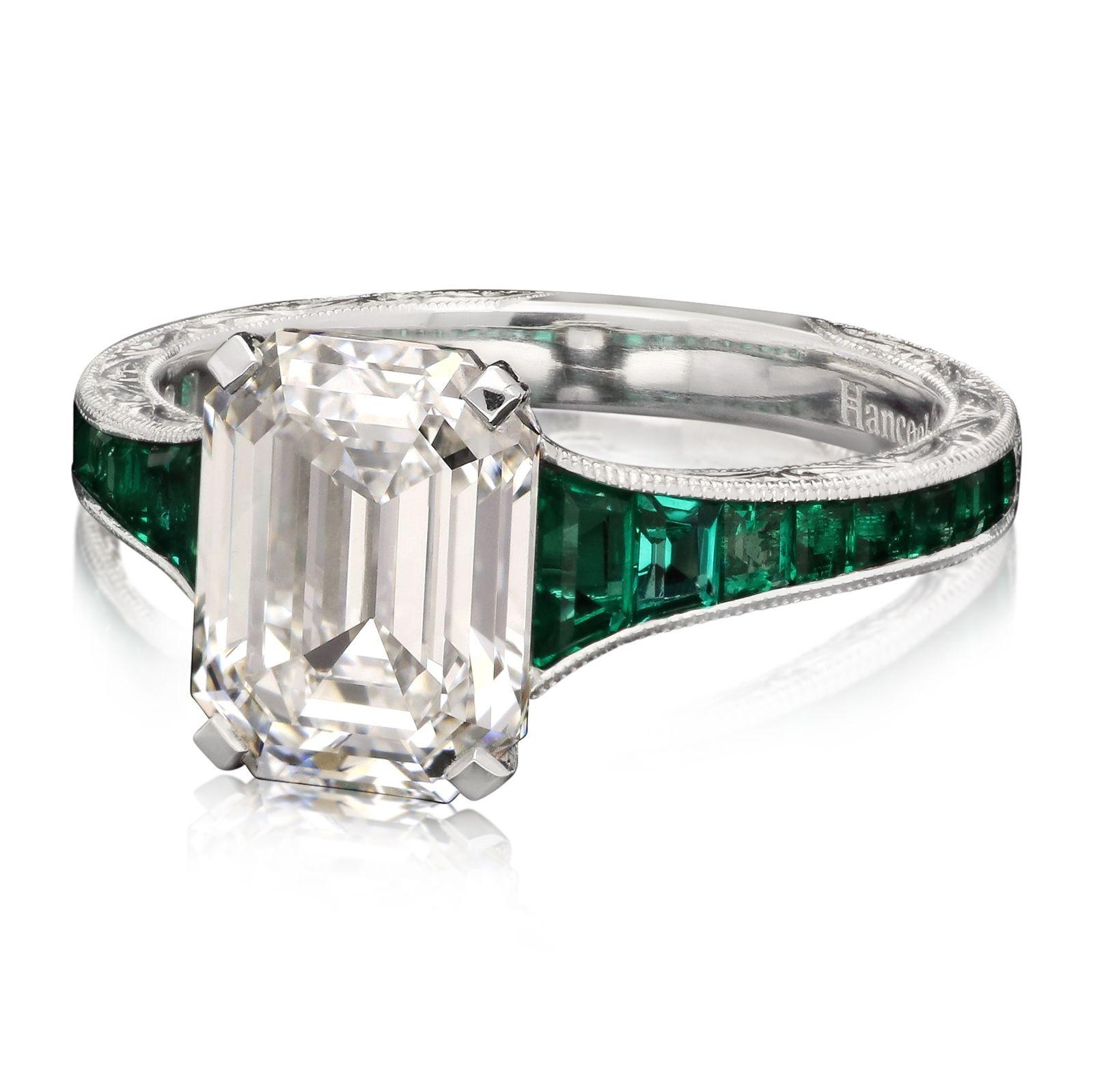A beautiful diamond and emerald ring by Hancocks set to the centre with a stunning emerald-cut diamond weighing 2.85ct and of D colour and VS2 clarity, in a corner claw setting between tapering shoulders set with 0.85cts of rich green calibre-cut