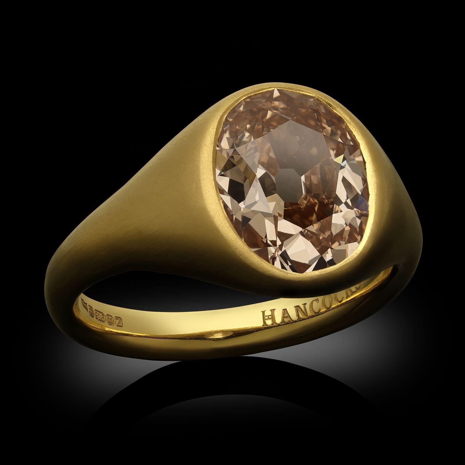 A handcrafted old cut fancy coloured diamond and gold gypsy set ring by Hancocks. The ring is set in the centre with an antique oval cut diamond of Fancy Brownish Yellowish Orange colour, weighing 3.01ct set flush in a band-style 22ct yellow gold