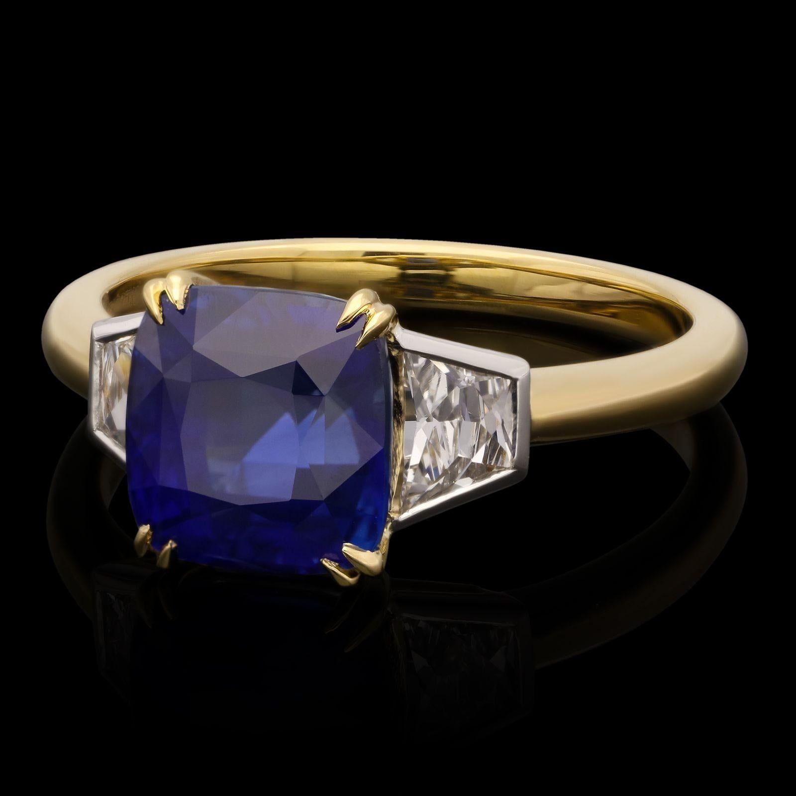 A beautiful sapphire and diamond ring by Hancocks centred with a cushion shaped sapphire of intense rich blue colour weighing 3.54cts claw set in 18ct yellow gold between shoulders rub over set with trapezoid shape French cut diamonds in platinum,