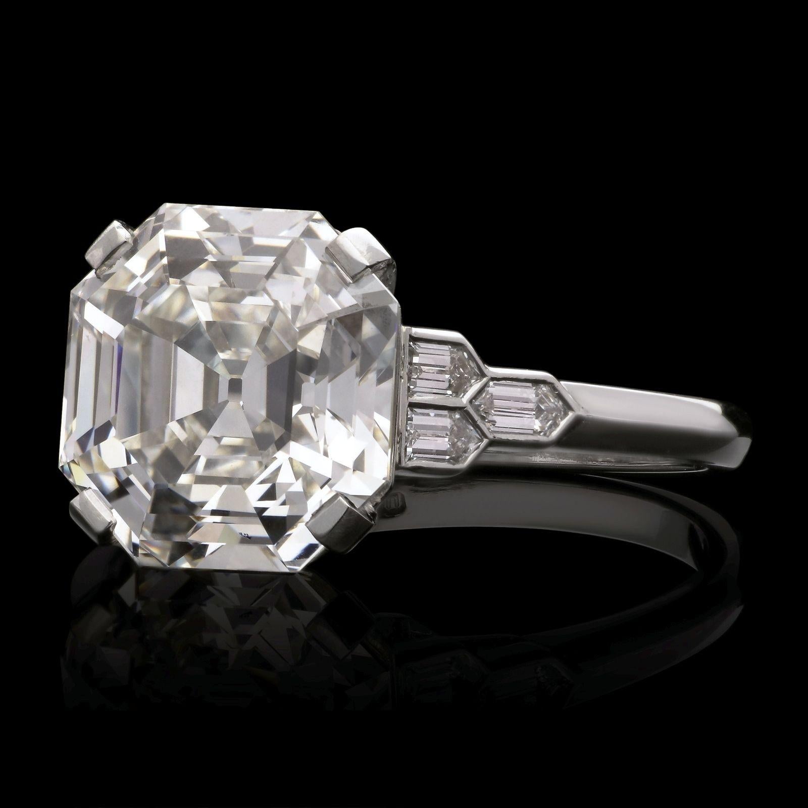 An elegant step cut diamond ring by Hancocks, set to the centre with a beautiful old cut Asscher diamond weighing 5.14cts and of H colour and VS2 clarity in corner claws to a simple double bar gallery between shoulders set each side with three
