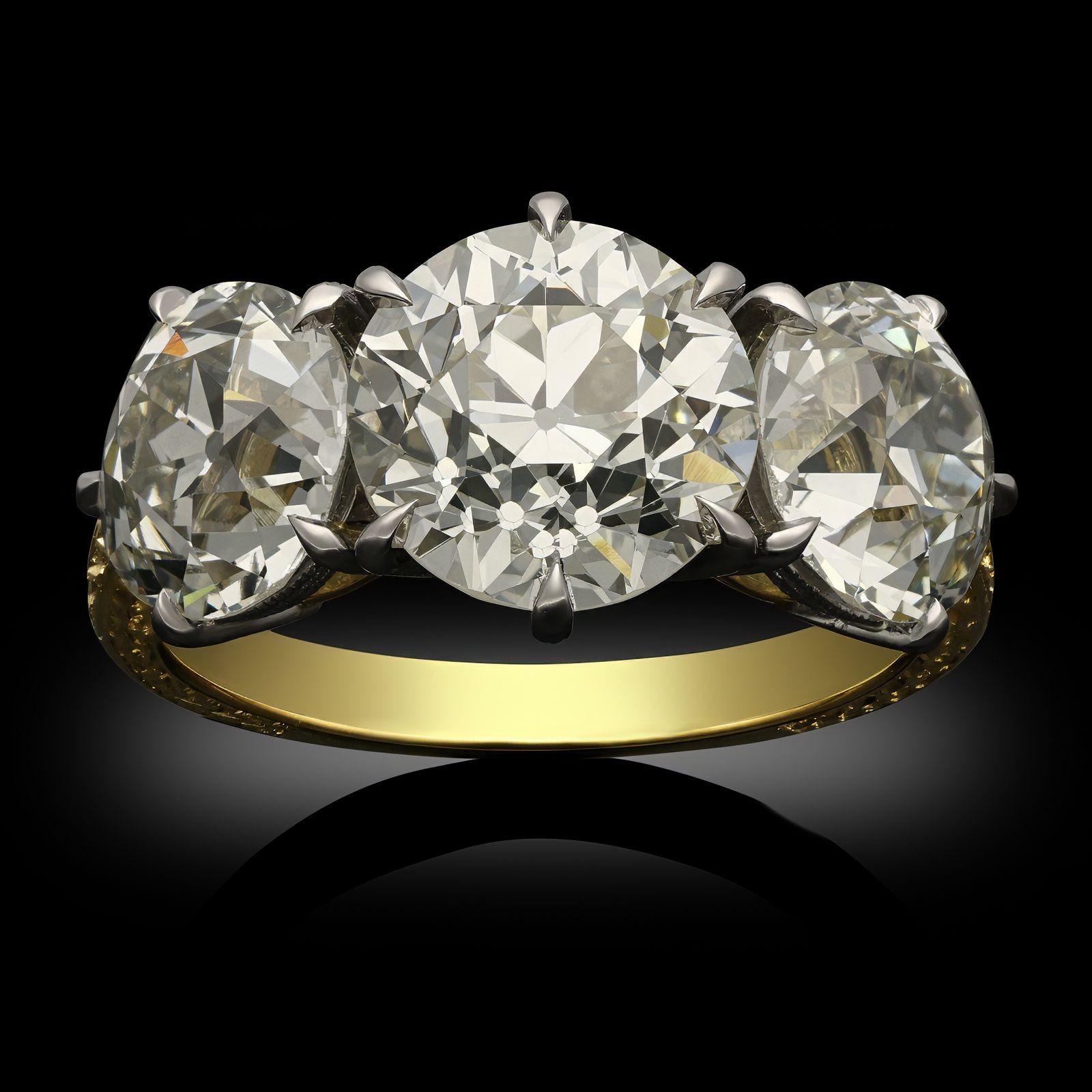 An old cut three stone diamond and 18ct yellow gold ring by Hancocks. The handcrafted ring has a 3.00ct old European cut diamond in the centre and is set between two more old European cut diamonds of 1.87ct and 1.90ct, all claw set in platinum to a