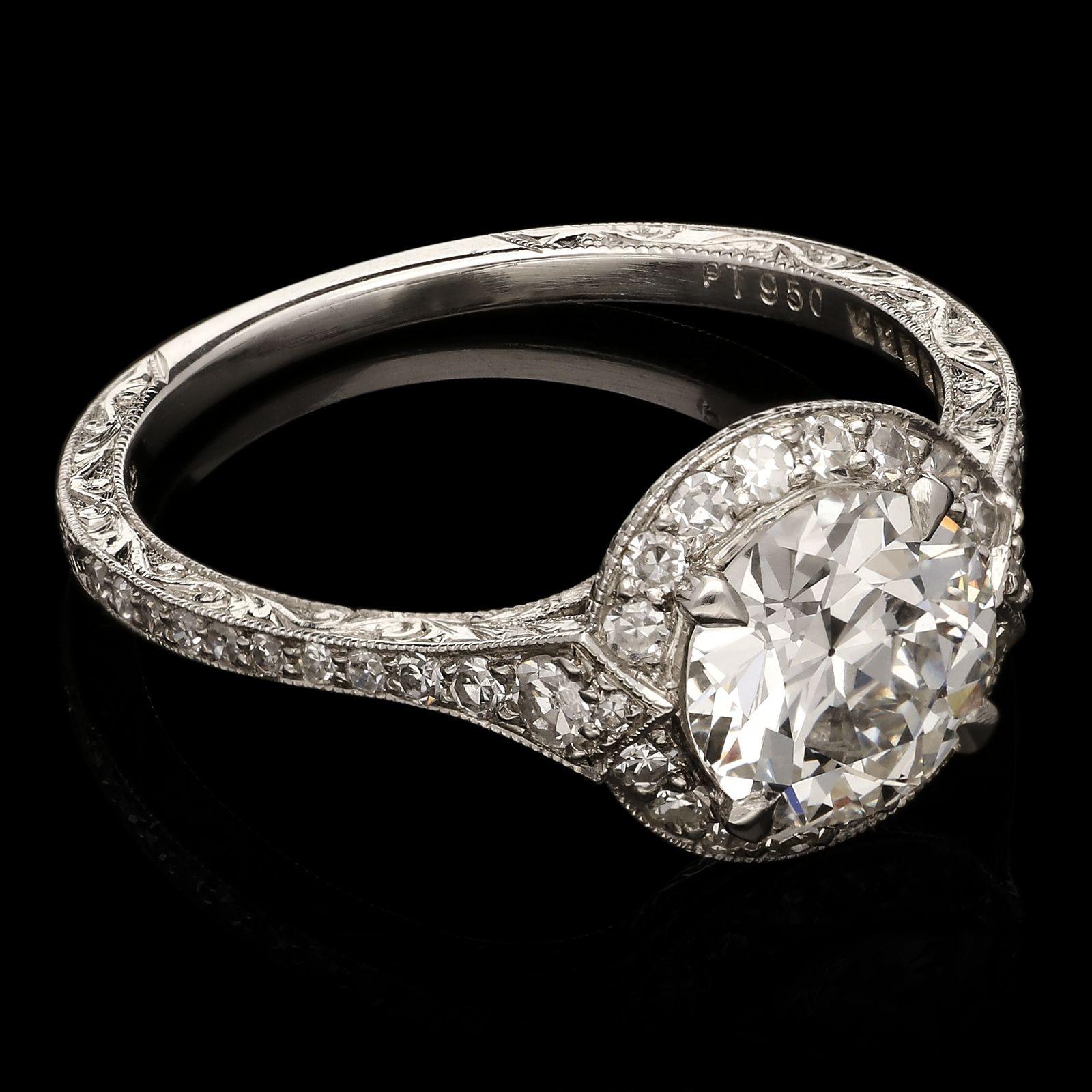 A beautiful brilliant cut diamond halo ring by Hancocks, the ring centred on a bright and lively round brilliant cut diamond weighing 1.28cts and of G colour and VS2 clarity claw set within a narrow single-cut diamond halo surround with millegrain